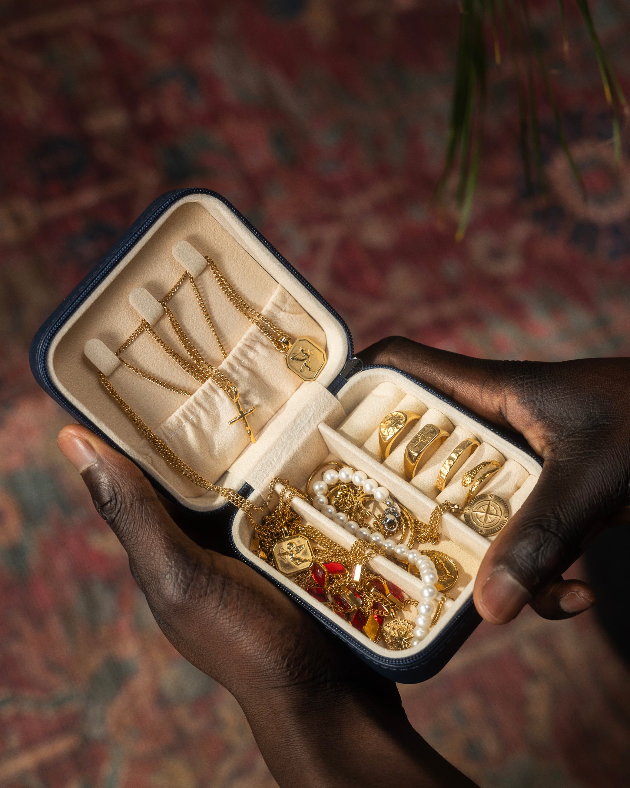 Open jewelry case on a wooden surface filled with gold jewelry including rings bracelets and chains