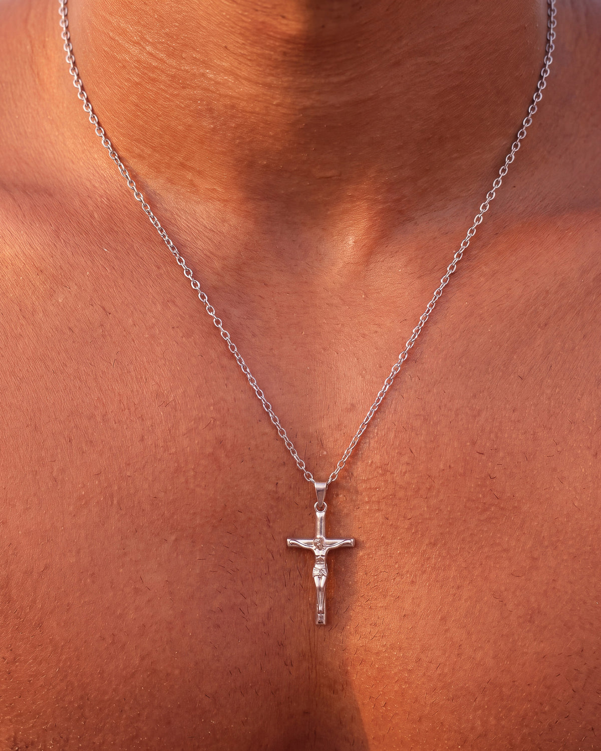 Primer plano del colgante de crucifijo de plata con la cadena sobre el pecho