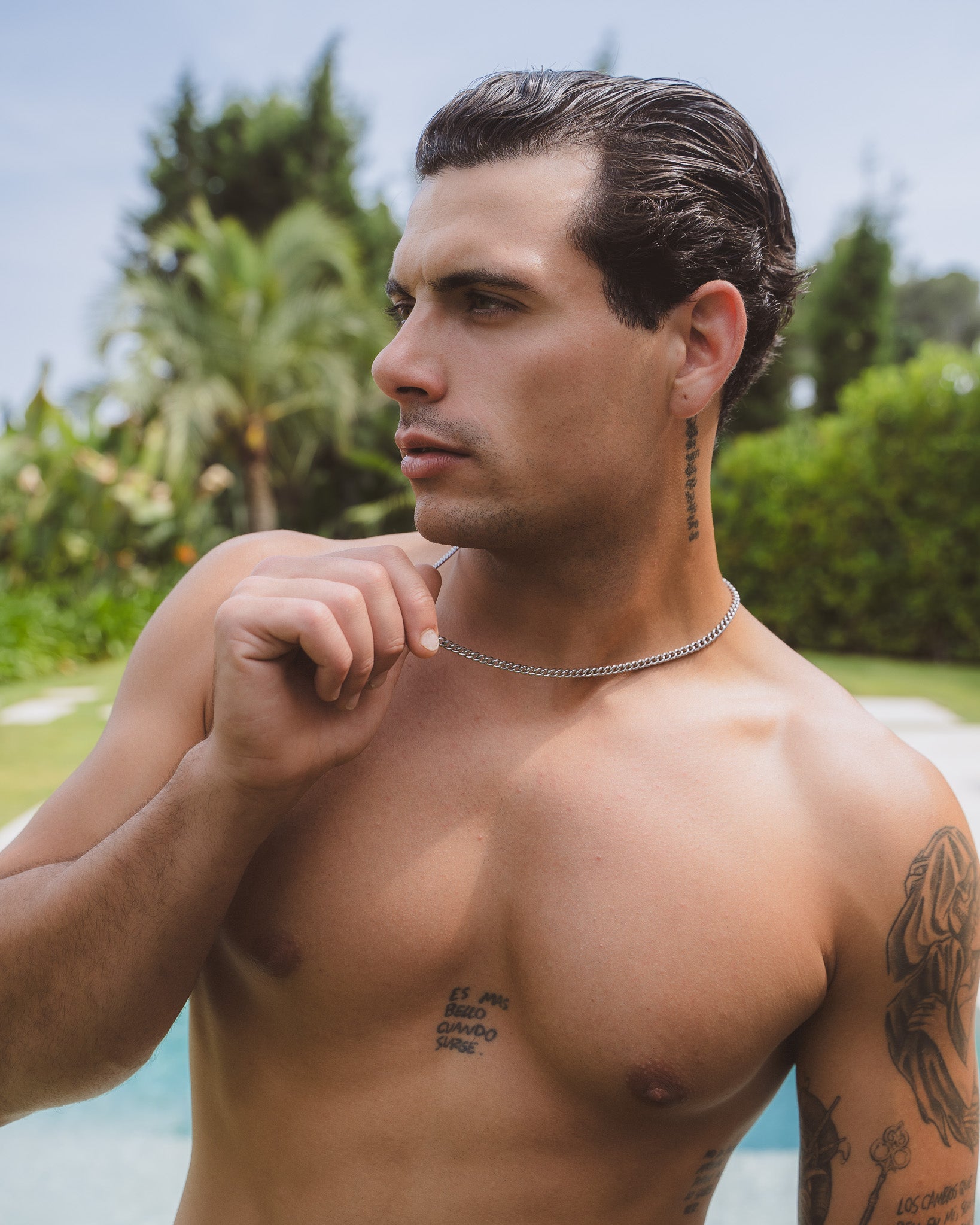 Front view of a man wearing a 5 mm Cuban silver chain with visible chest tattoos.
