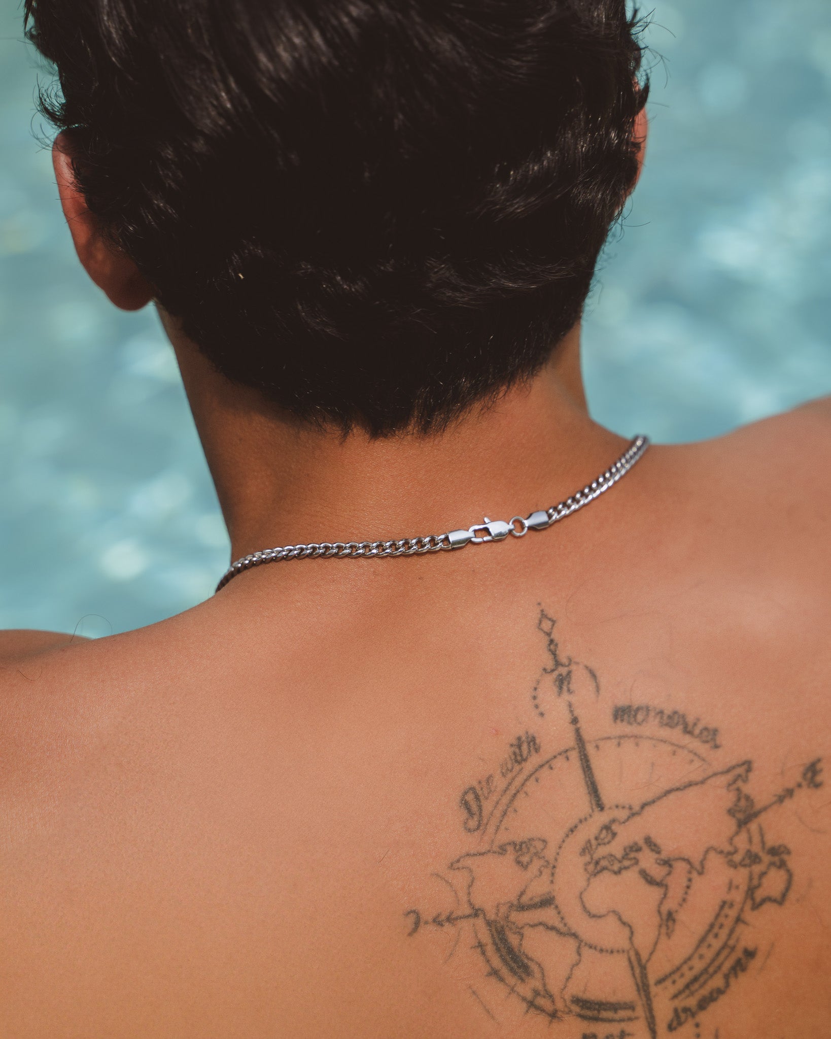 Cuban silver chain resting at the nape of the neck, 5 mm wide.