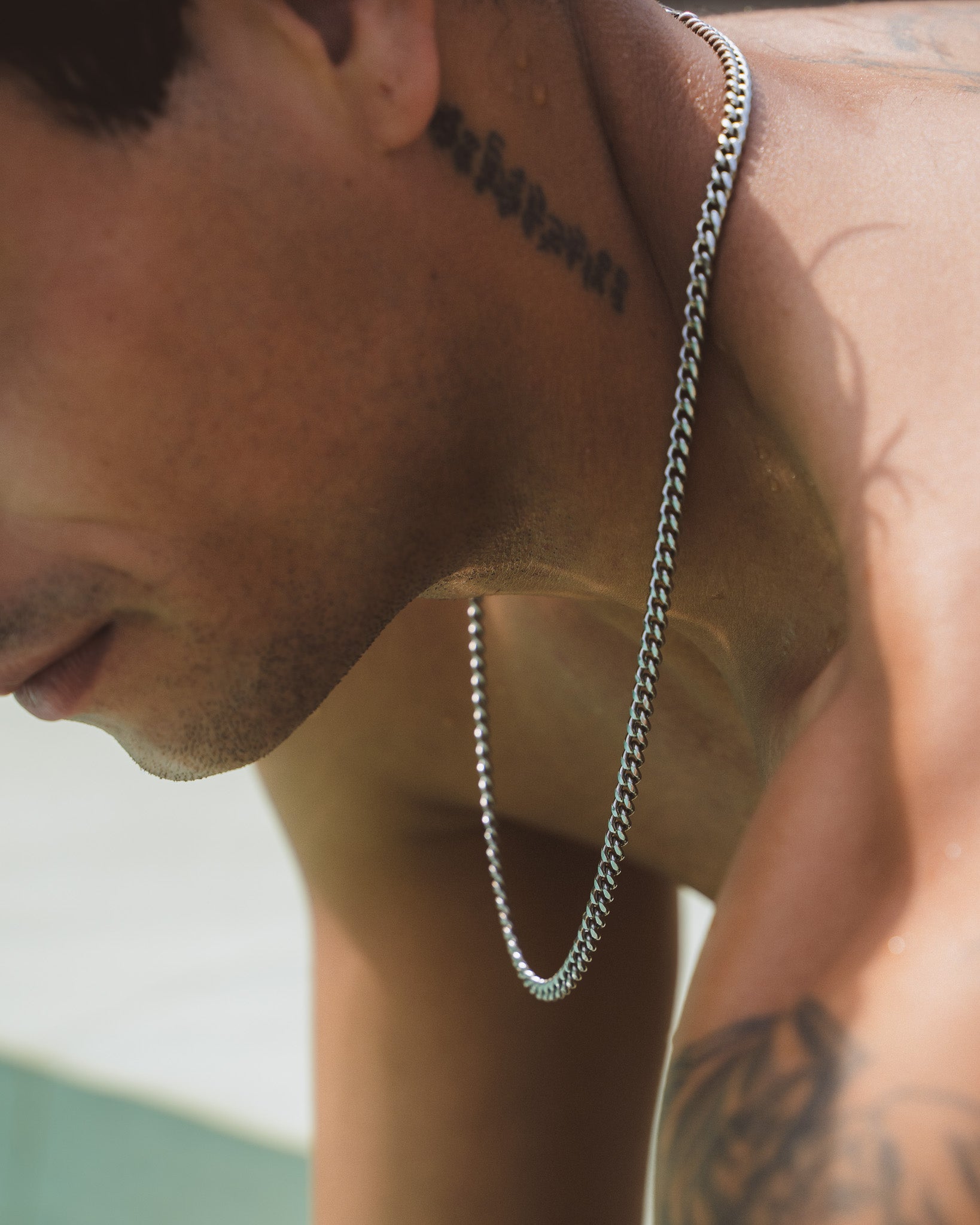 Side profile of a man wearing a 5 mm Cuban silver chain around the neck.