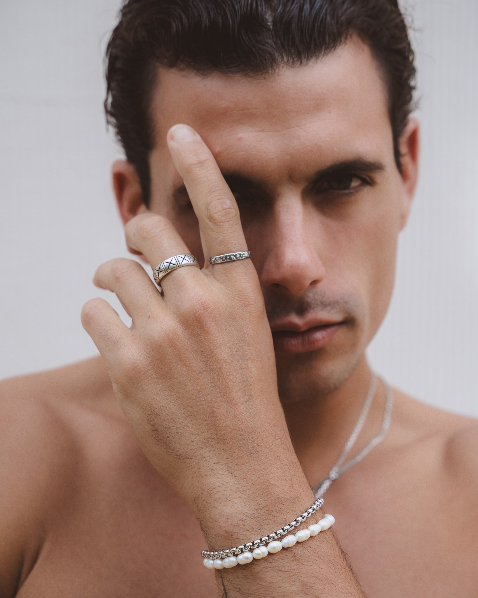 Anillo plateado con patrón entrecruzado en un dedo con una segunda banda sencilla cerca