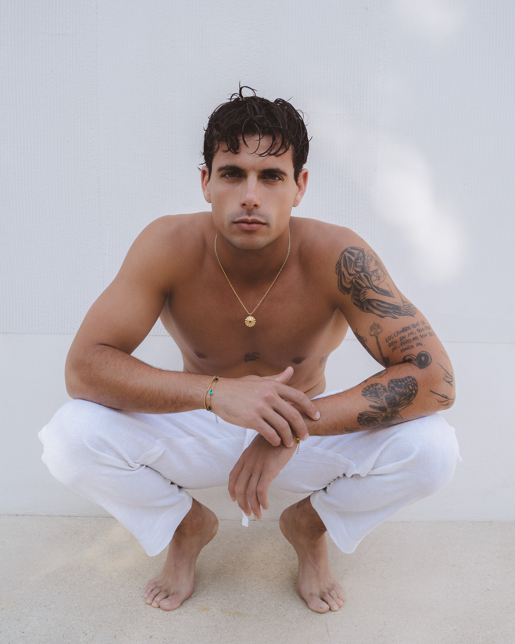 Male model wearing the silk gold necklace with a sunburst pendant