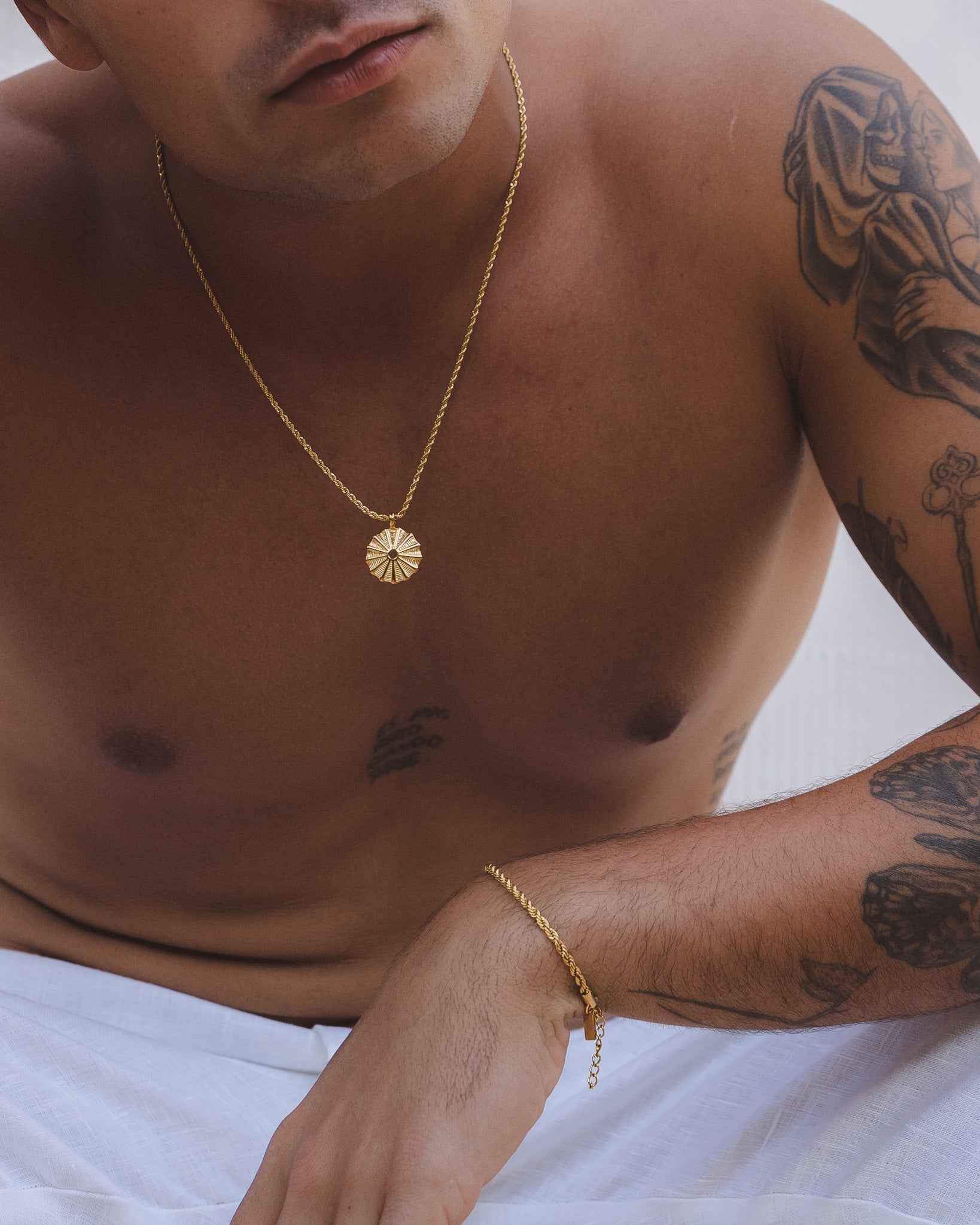 Close up of the gold sunburst pendant on a delicate chain against the chest