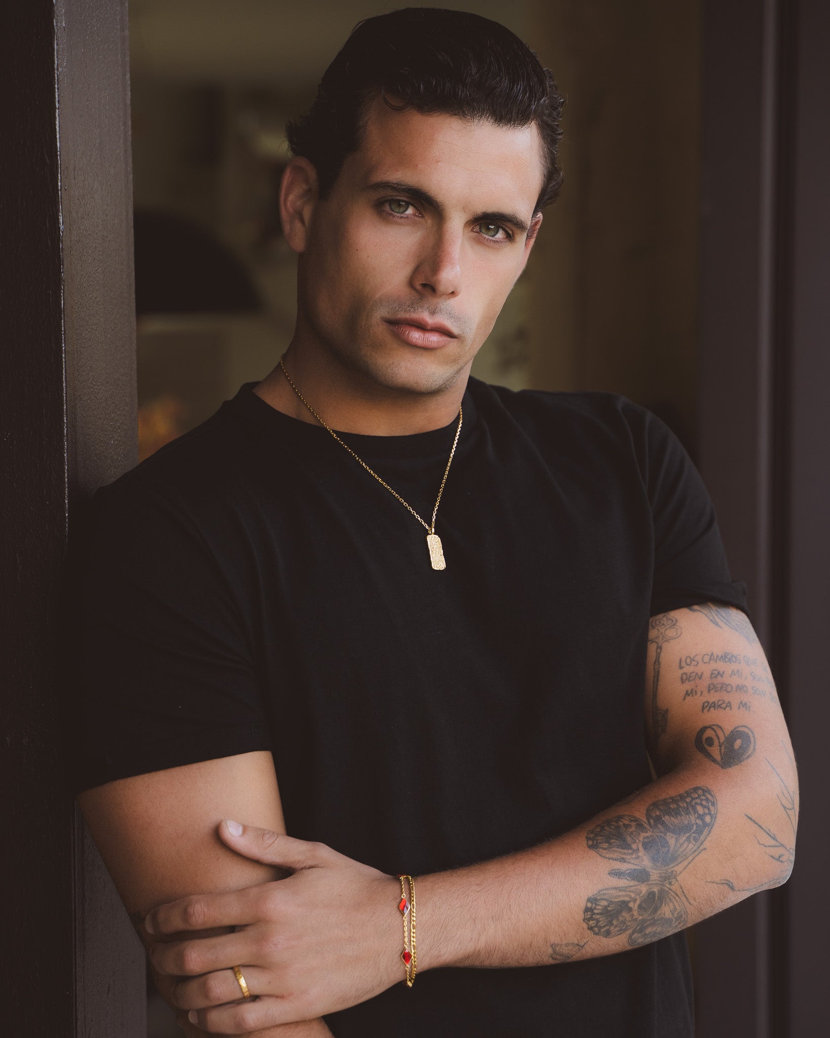 Moonrock gold necklace with a textured rectangular pendant worn over a black shirt