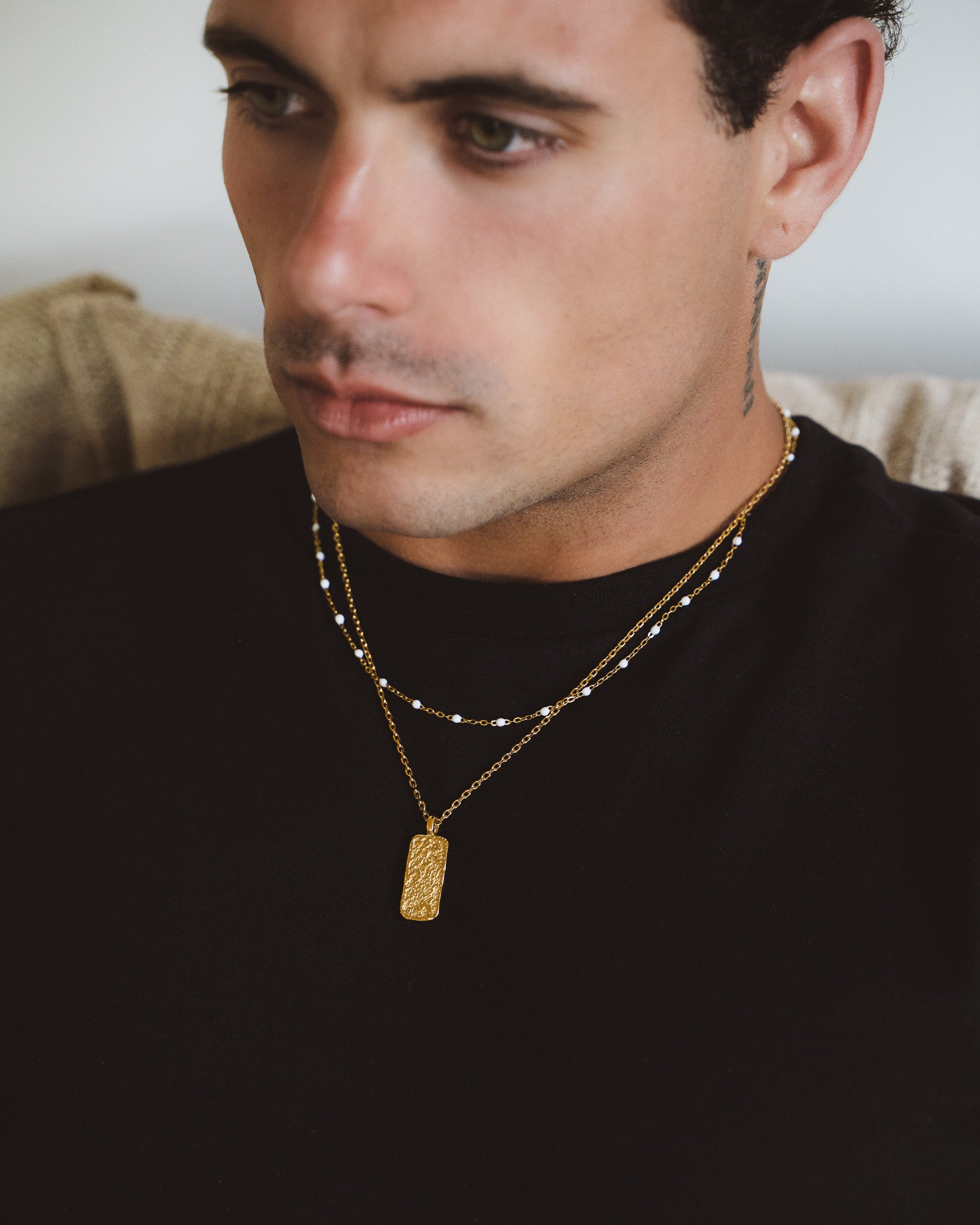 Moonrock gold necklace with a textured rectangular pendant on layered chains worn by a man