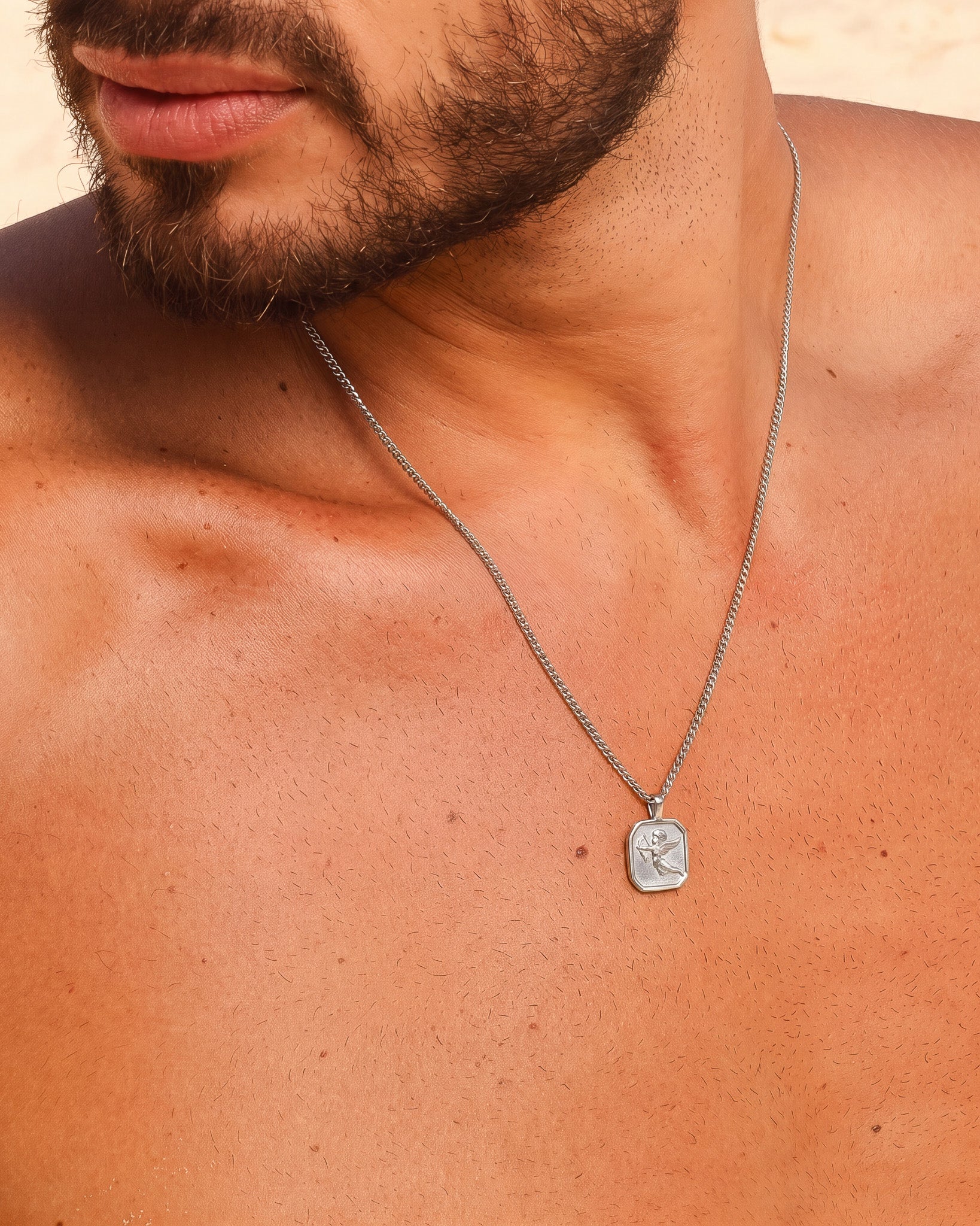 Close up of a man wearing a Savior silver necklace with a silver chain on bare chest