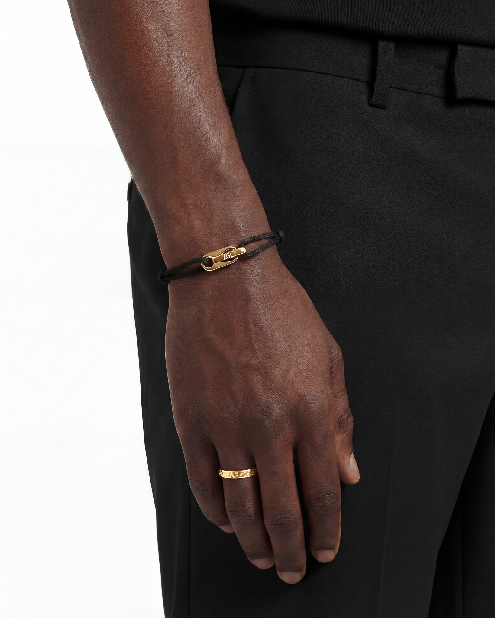 Gold Atlantis bracelet with an LGC engraved clasp on the wrist against black clothing