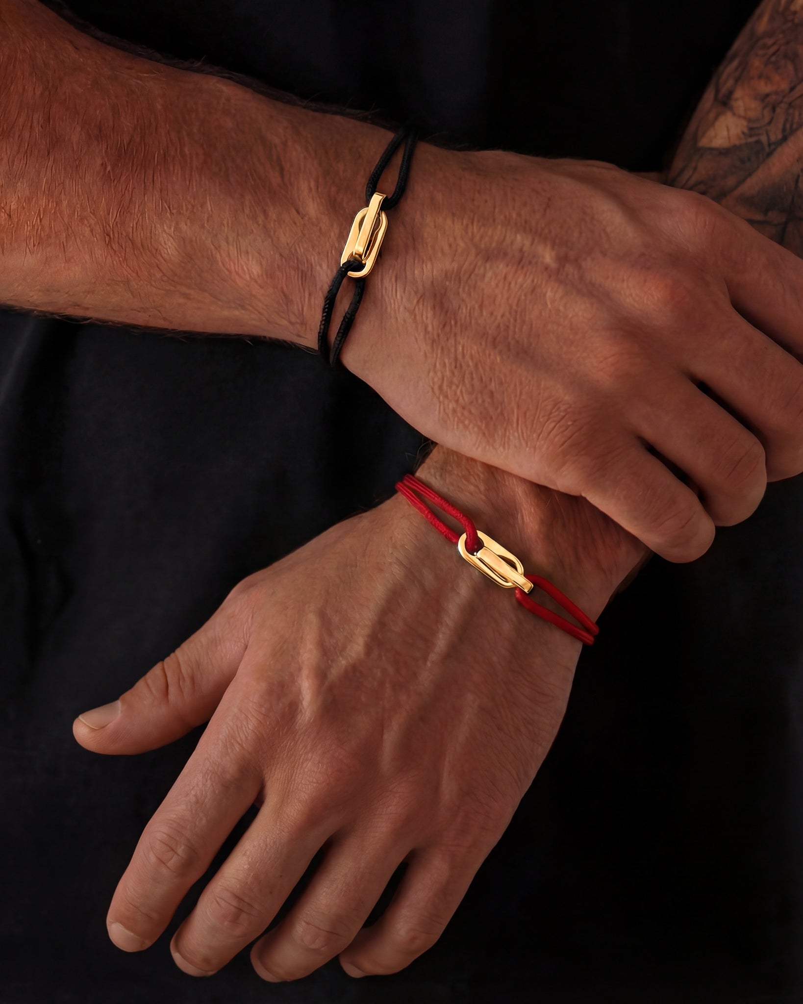 Close up of a gold Atlantis bracelet with a black cord strap worn on a wrist