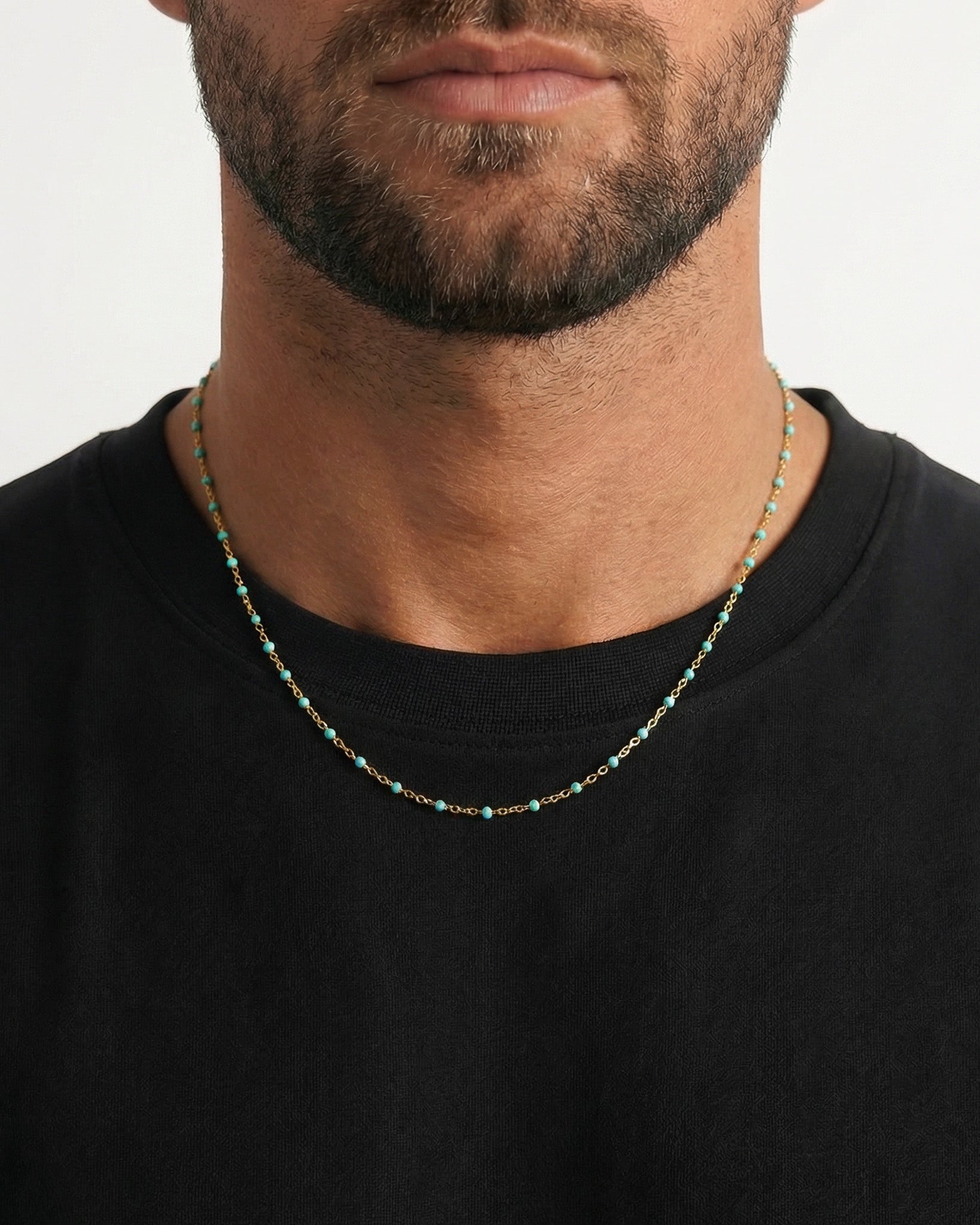 GEM Gold Chain with turquoise beads worn on a black shirt, close up of neck and chin.