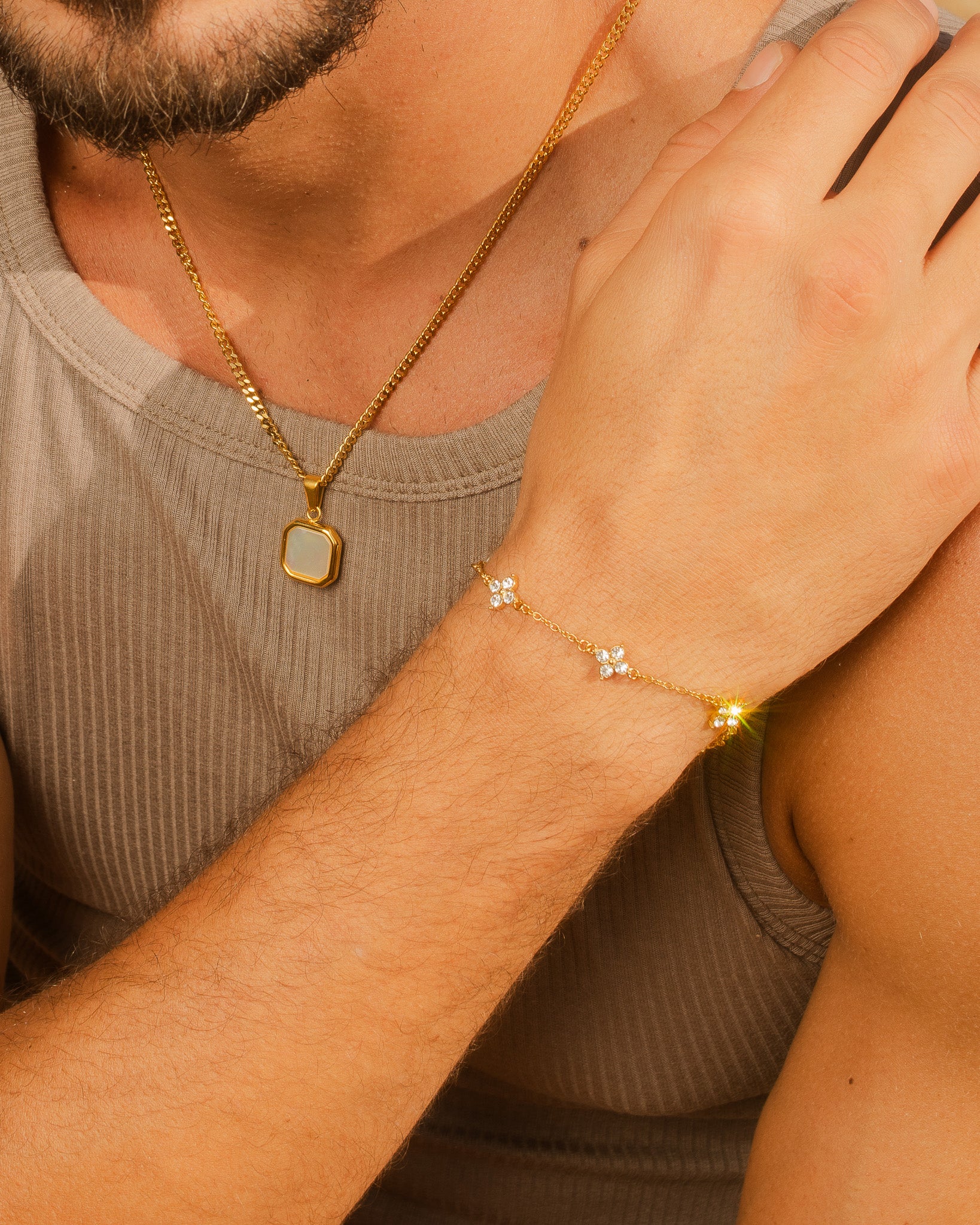 Gold Clover bracelet on the wearer's wrist with a gold pendant necklace visible at the chest.