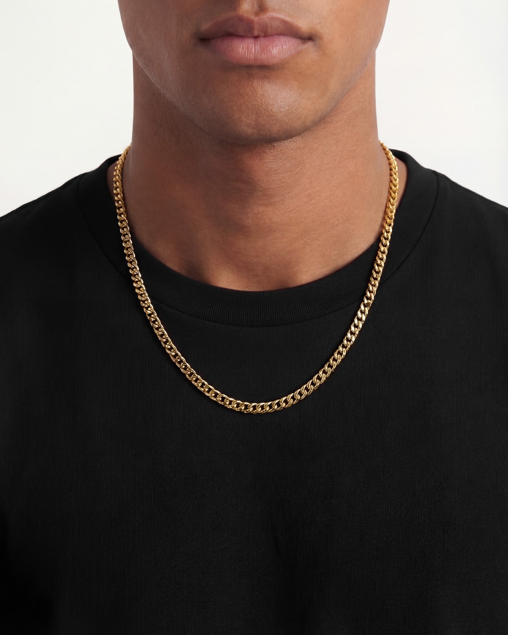 Male model wearing a 5mm Cuban link gold chain around the neck and a ring on his finger
