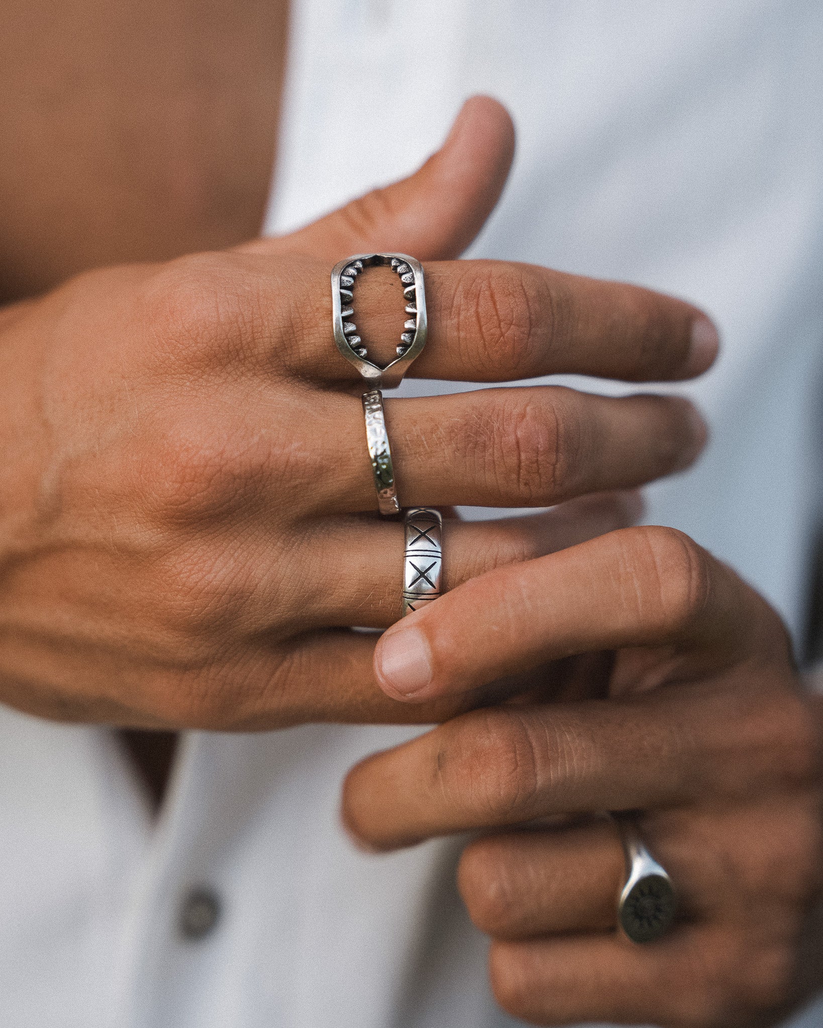 Dusky silver ring with jagged toothlike interior edge on finger