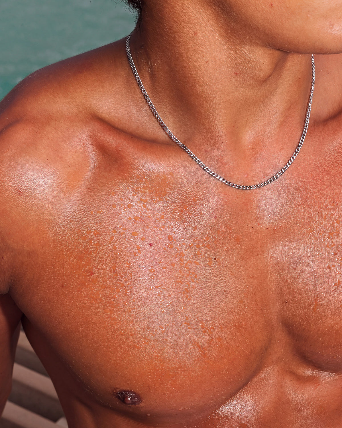 KUBU silver chain draped around a model's bare neck and collarbone.