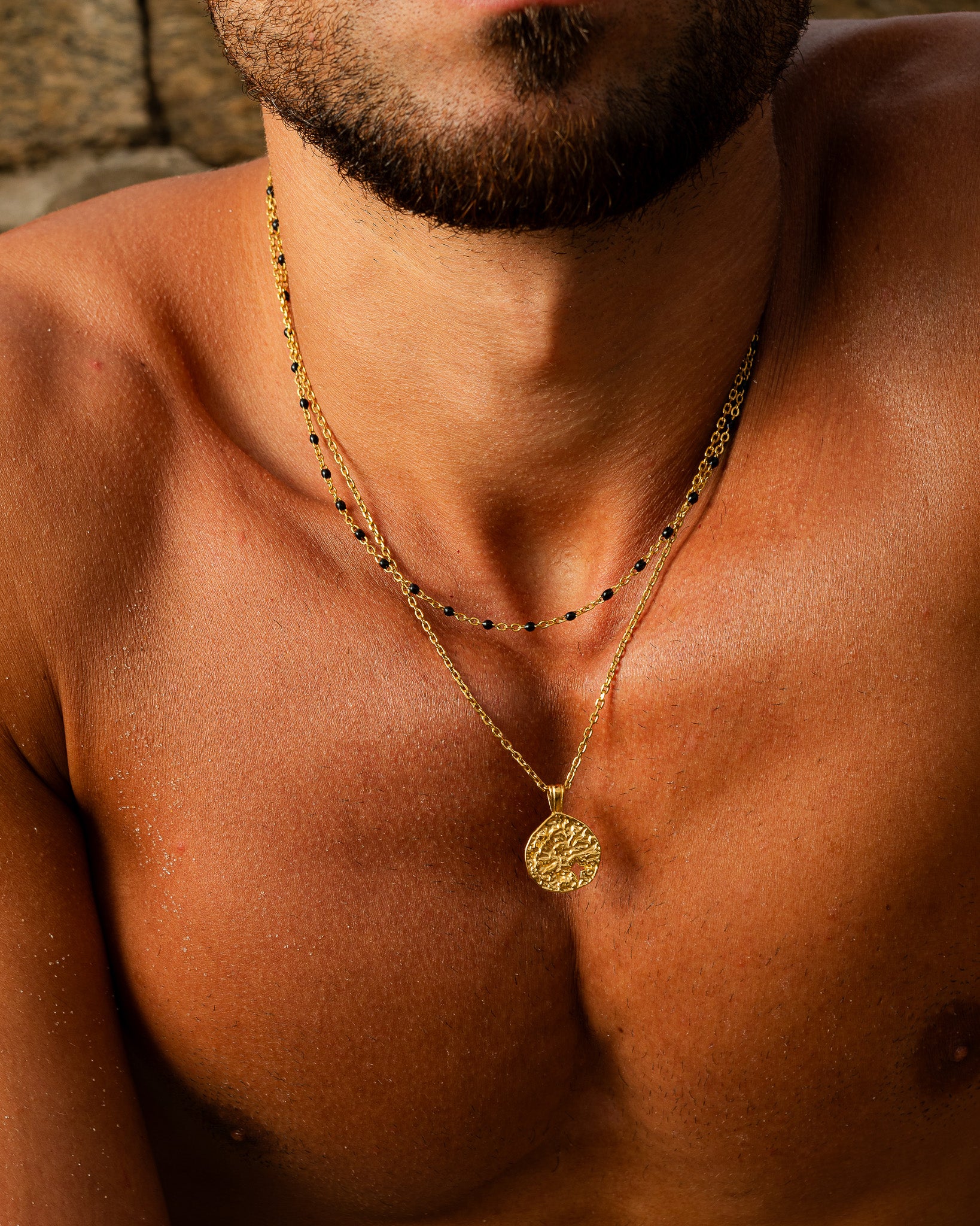 MIST Gold Necklace with black beads and a textured round pendant resting on the model's chest