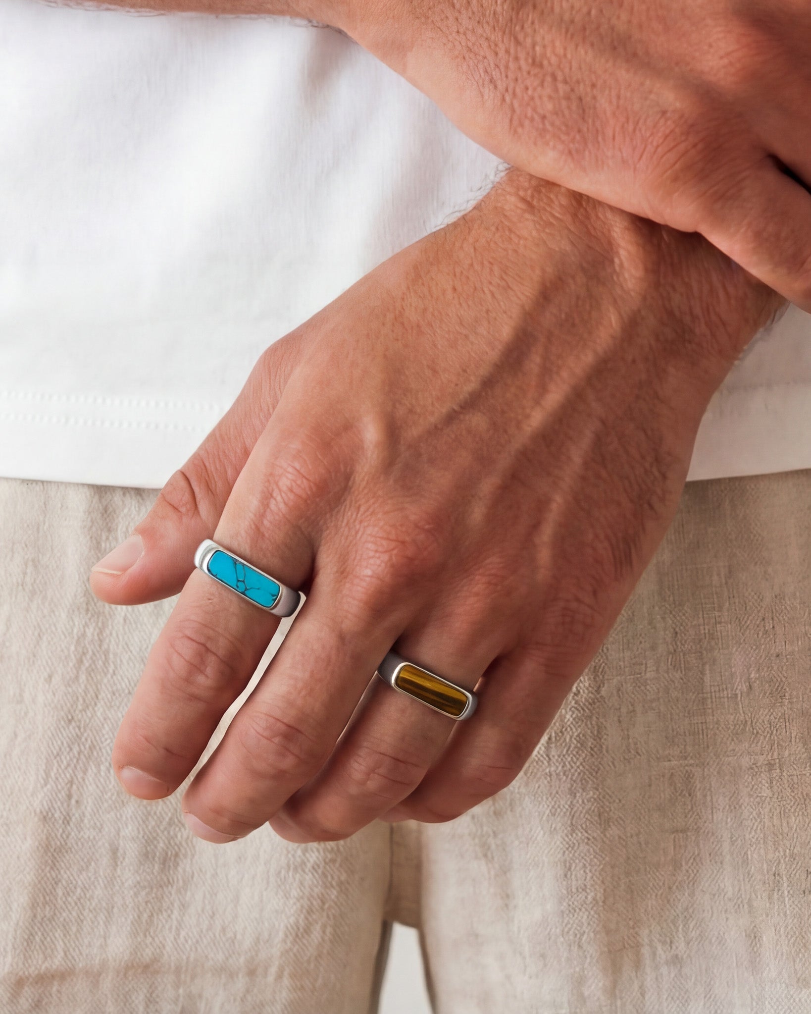 Mano con NOVA SILVER RING con incrustación turquesa en el dedo sobre fondo claro