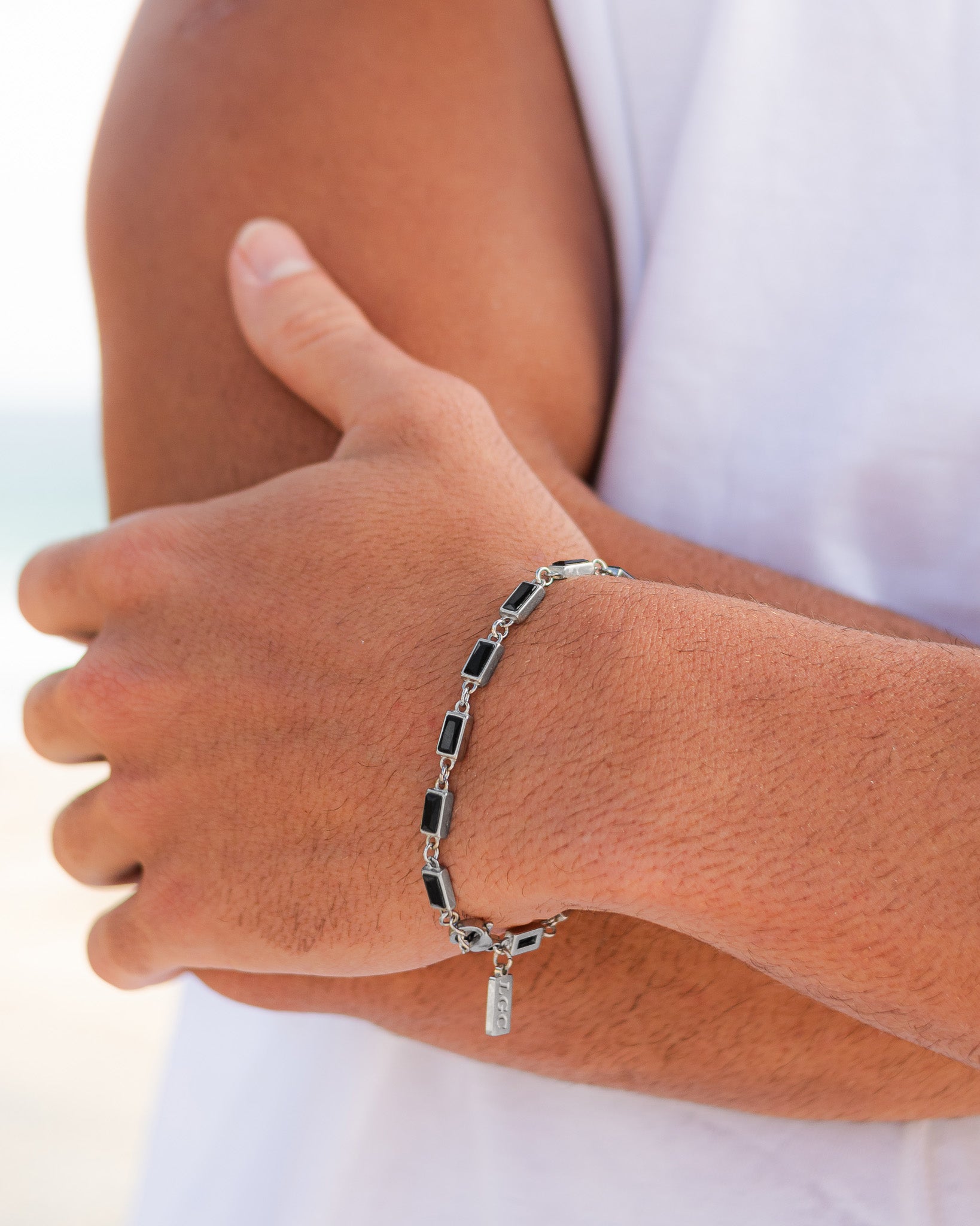 Silver OMEN bracelet with rectangular black stones worn on the wrist