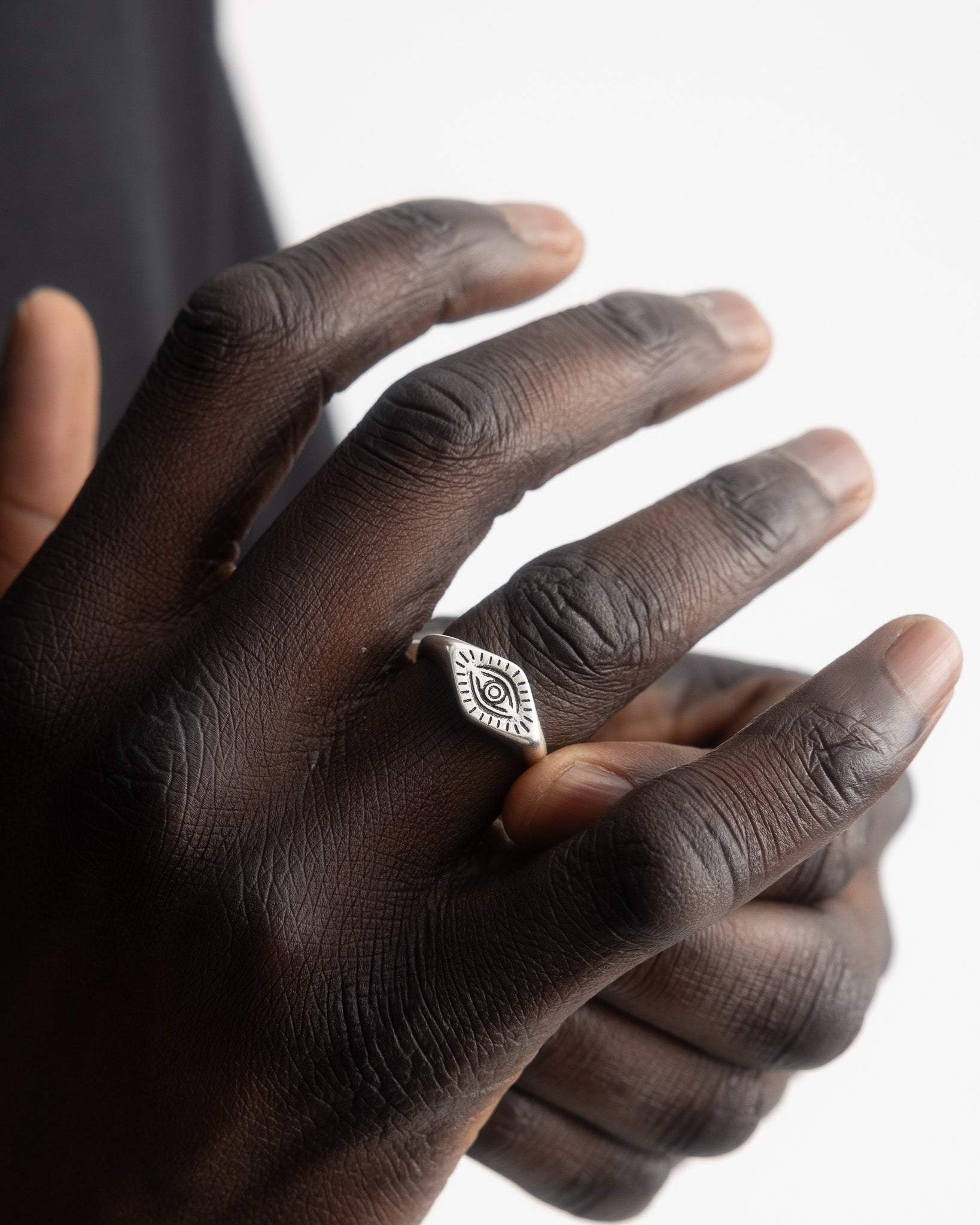 Mano con el anillo plateado ORUS con motivo de ojo en una banda fina.