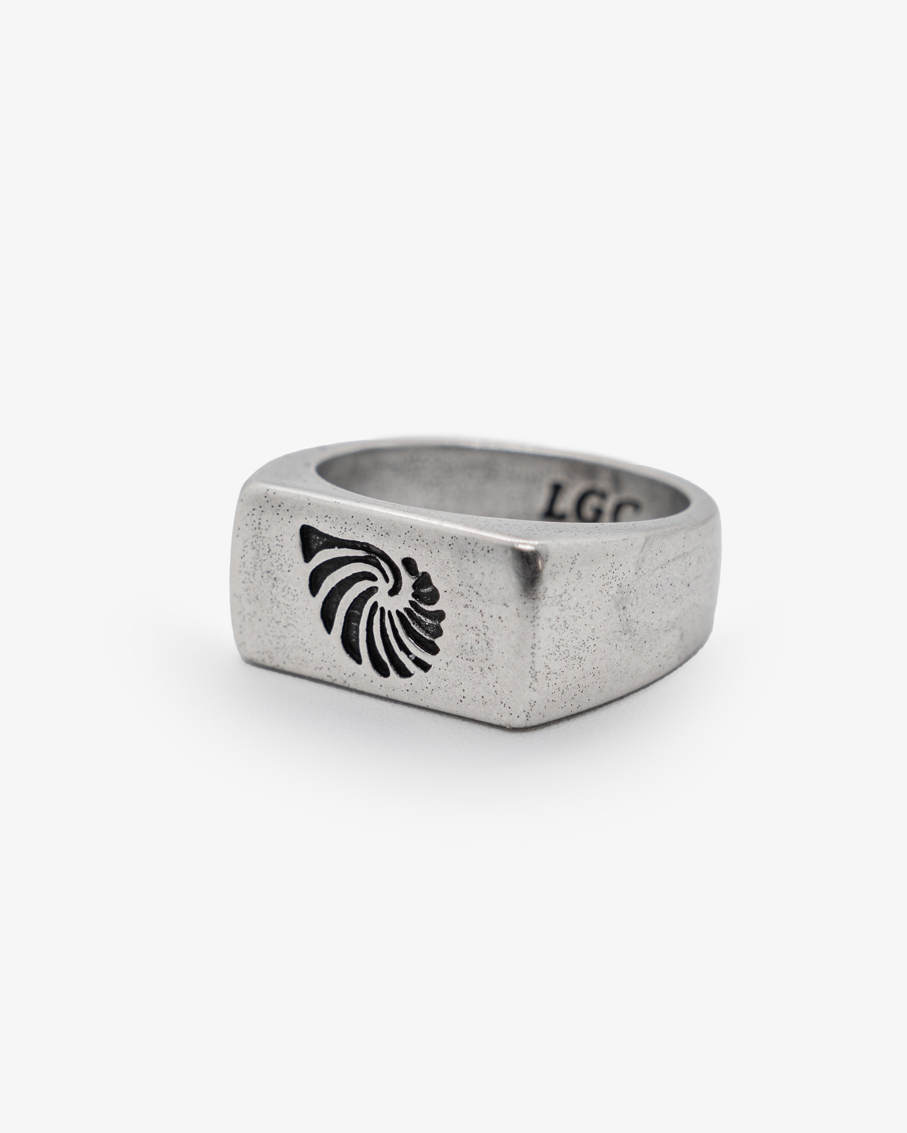 Primer plano de un anillo de concha gris moteado con diseño de concha negra en el lateral.