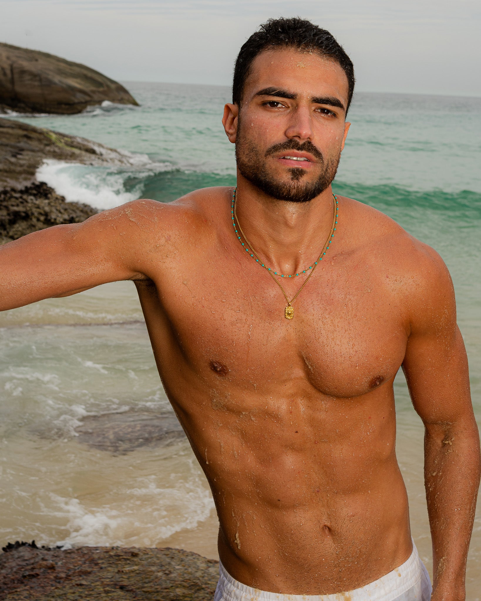 IBZ GOLD NECKLACE turquoise bead necklace with a gold pendant on a shirtless man by the sea