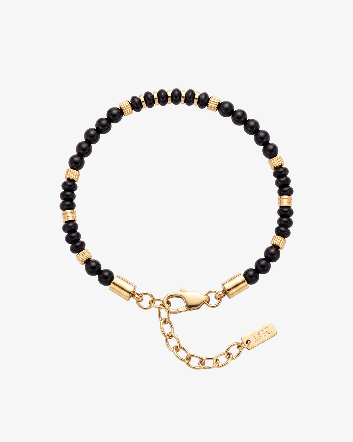 Pulsera de cuentas de ágata negra con separadores cilíndricos de oro en la muñeca