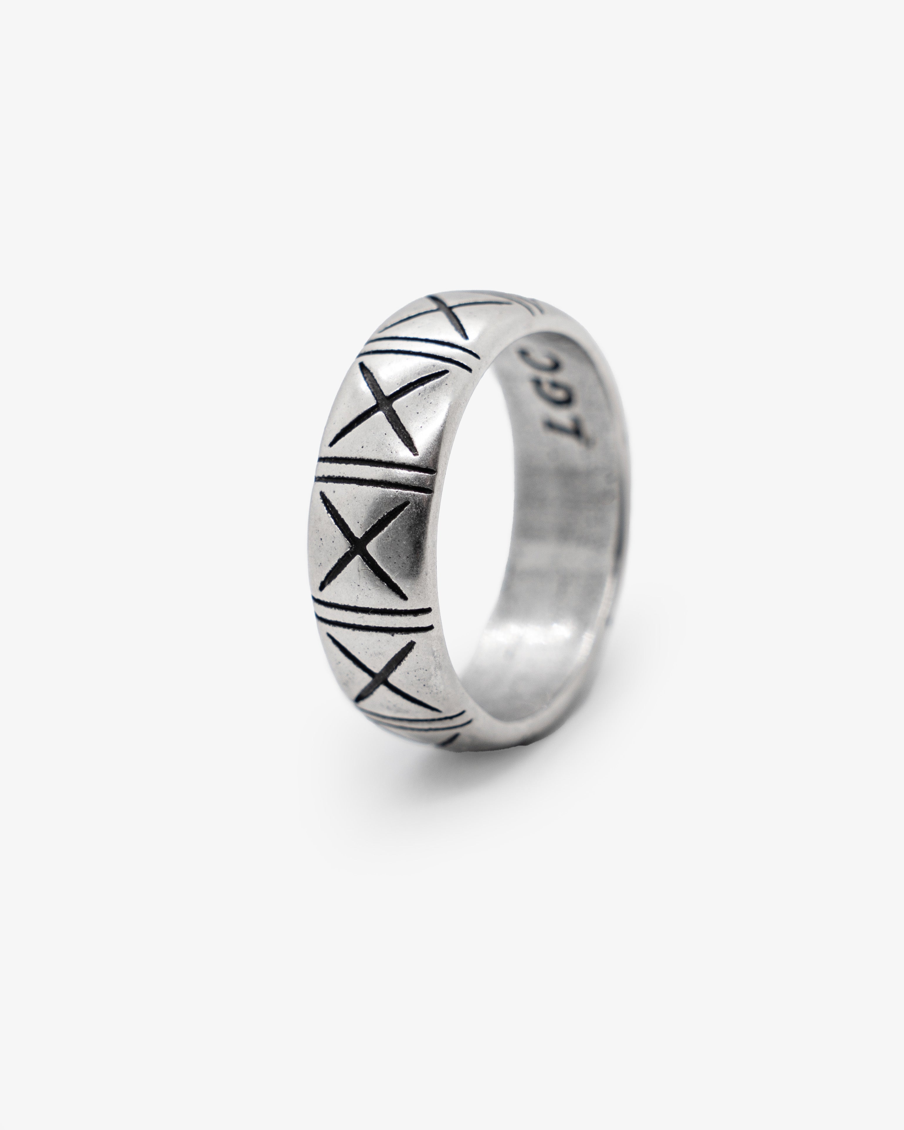 Primer plano de un anillo plateado TNF con grabados de X alrededor de una banda redondeada