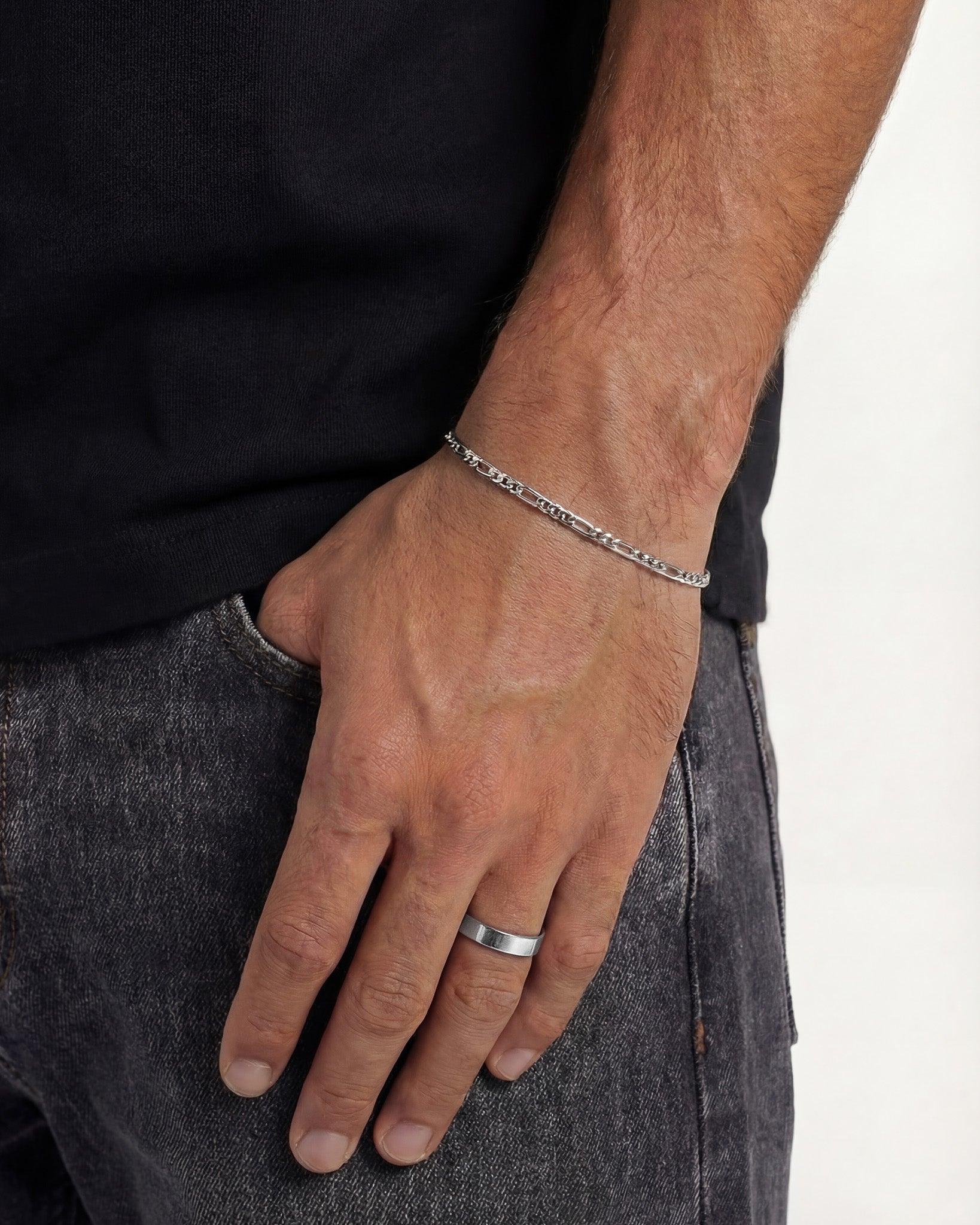 Vista lateral de una mano con el anillo plateado VERO en el dedo anular y pulsera de cadena plateada en la muñeca