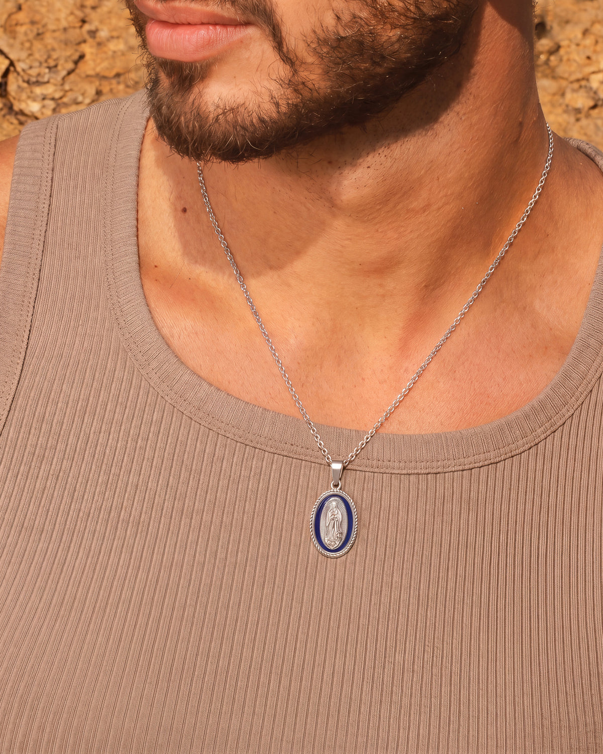 Hombre con collar plateado de la Virgen María con medallón ovalado de esmalte azul