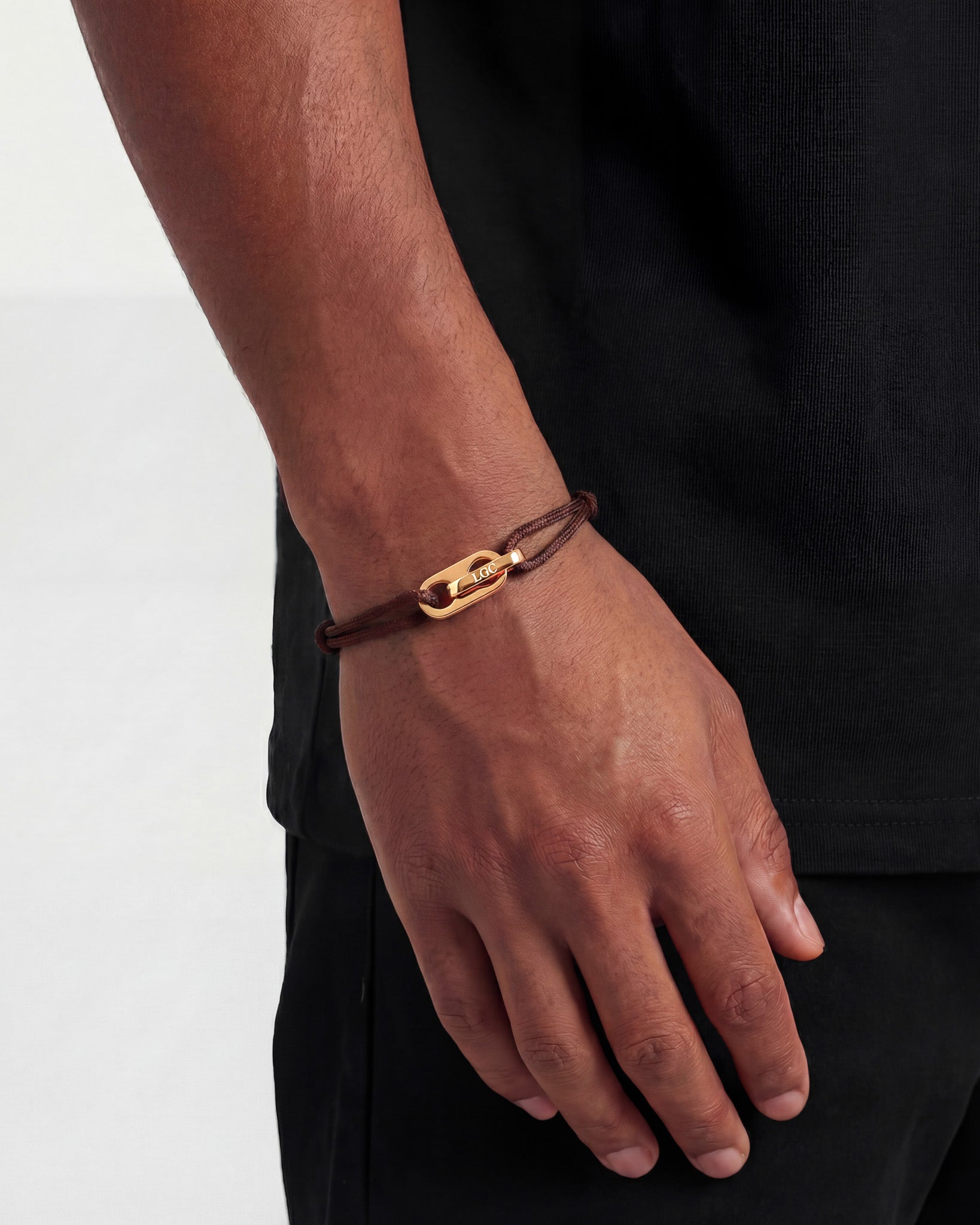 Close-up of Atlantis Gold Bracelet clasp on brown braided cord around the wrist