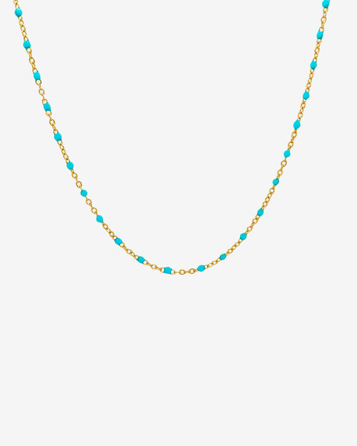 Collar de cadena dorada con cuentas turquesa sobre fondo blanco