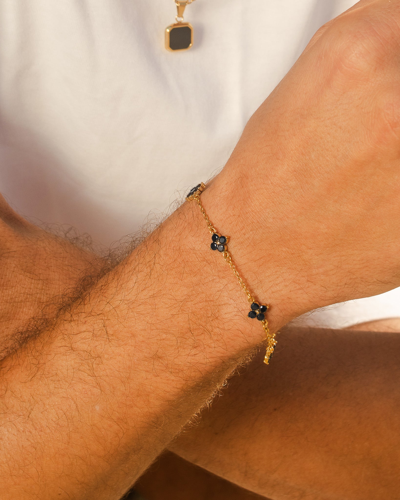 Clover gold bracelet with a black four-petal flower charm on the wrist