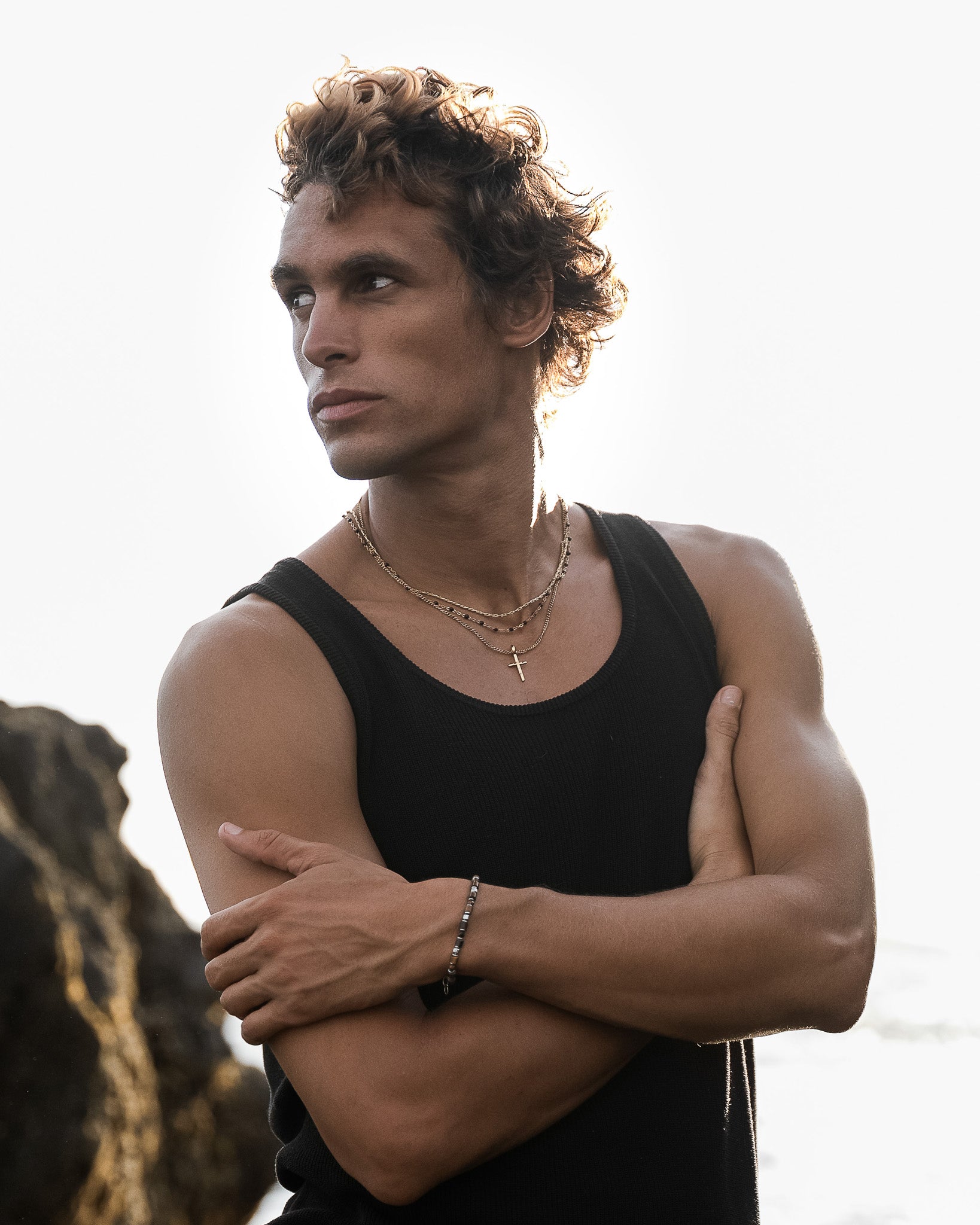 Front view of a model wearing layered gold chains with black beads and a gold cross pendant