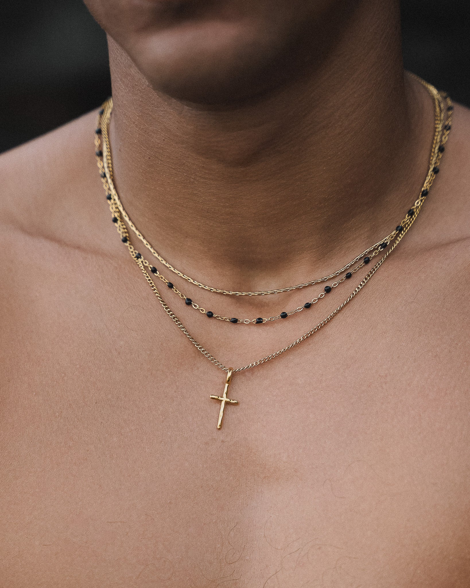 Layered gold necklaces with black beads resting on a model's neck