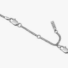 Primer plano de un extensor de cadena plateado de 8 cm con cierre de mosquetón sobre fondo pálido