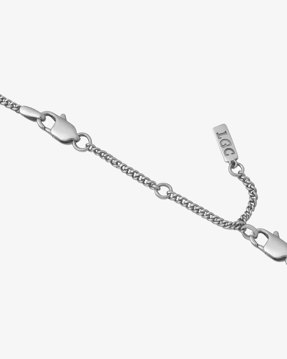Primer plano de un extensor de cadena plateado de 8 cm con cierre de mosquetón sobre fondo pálido