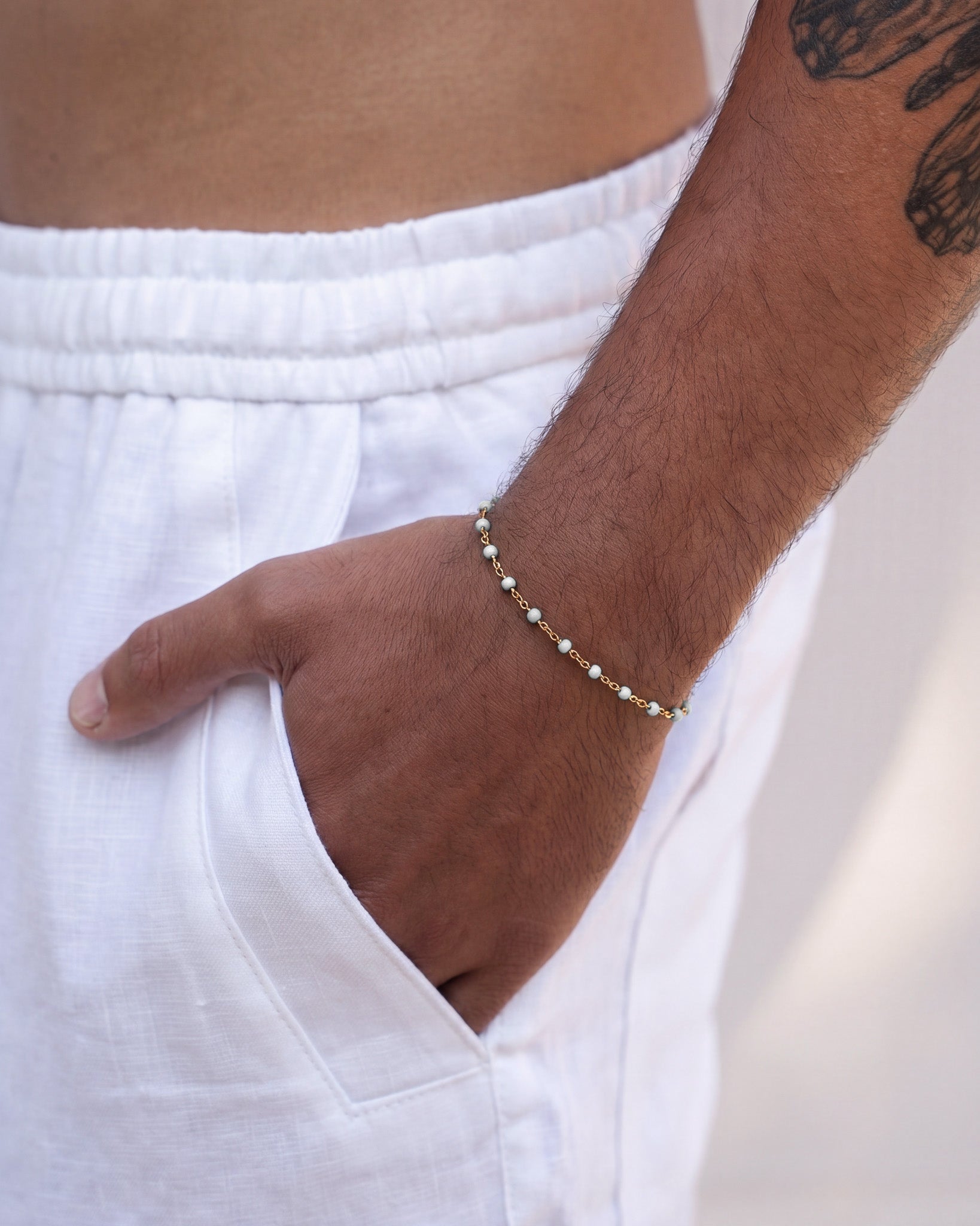 GEM GOLD BRACELET with pale blue beads on a gold chain around the wrist