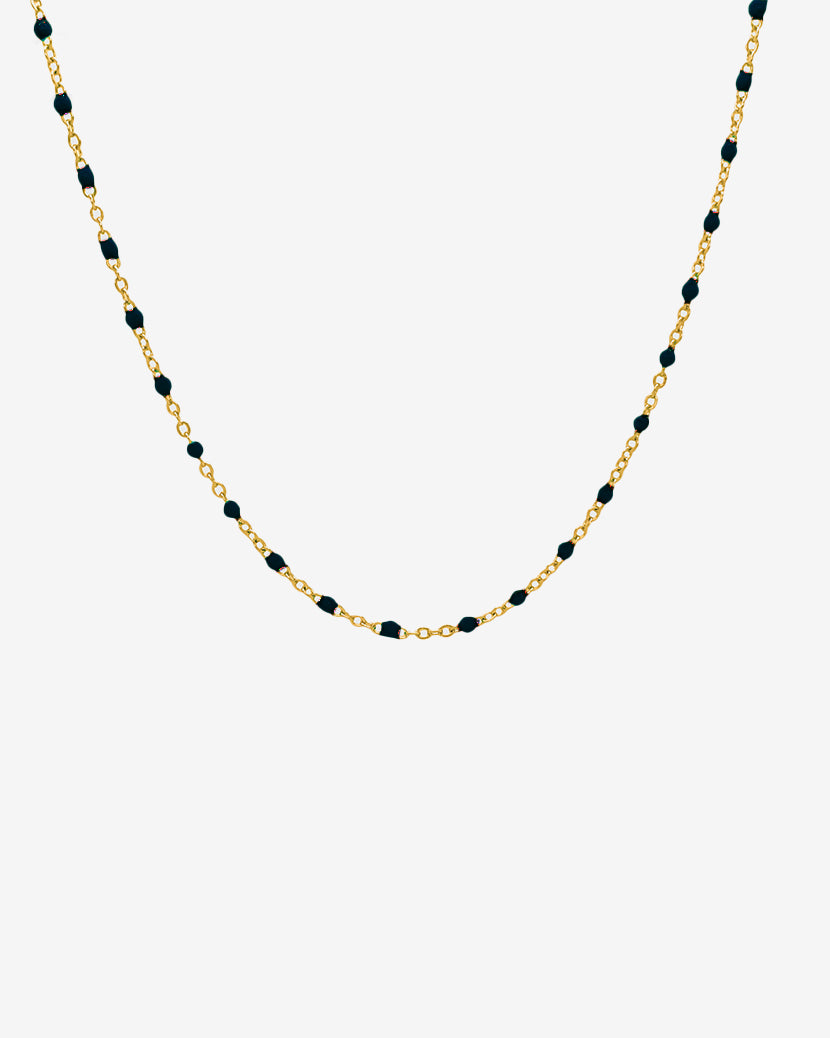 Collar de cadena dorada con cuentas negras espaciadas uniformemente, 50 cm de largo, sobre fondo blanco.
