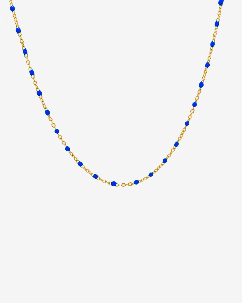 Collar GEM GOLD CHAIN con cuentas azules en cadena dorada sobre fondo blanco