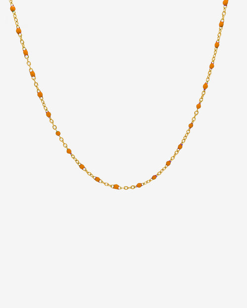 Collar de cadena dorada GEM con cuentas naranjas espaciadas en delicada cadena de eslabones dorados sobre fondo blanco