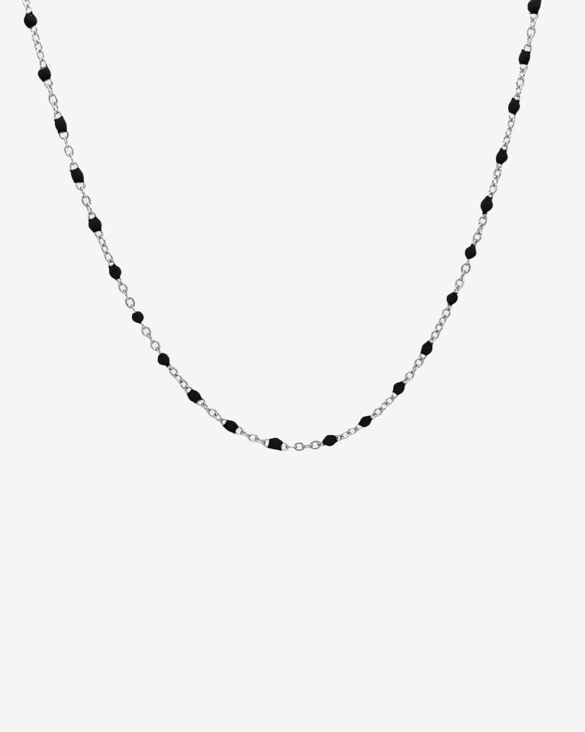 Collar de cadena plateada con cuentas negras espaciadas uniformemente sobre fondo blanco