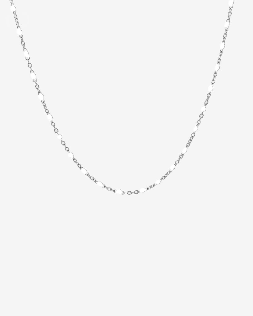 Delicado collar de cadena plateada con pequeñas cuentas blancas espaciadas uniformemente entre los eslabones