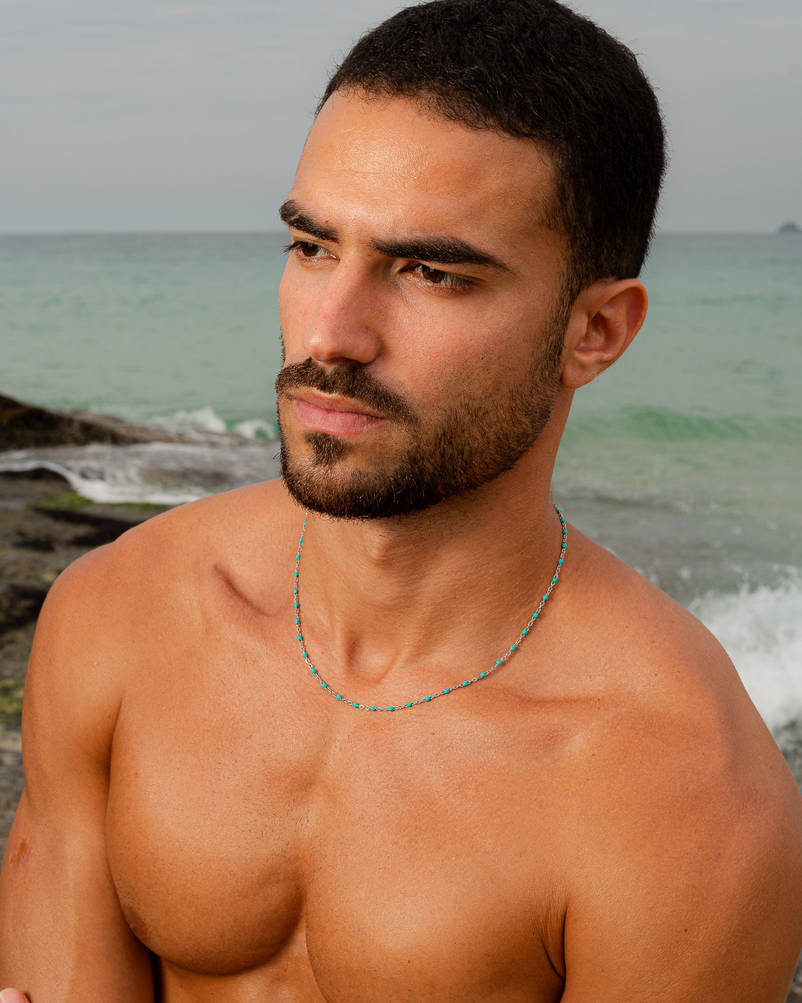 turquoise bead silver chain necklace worn around a man's neck at the chest