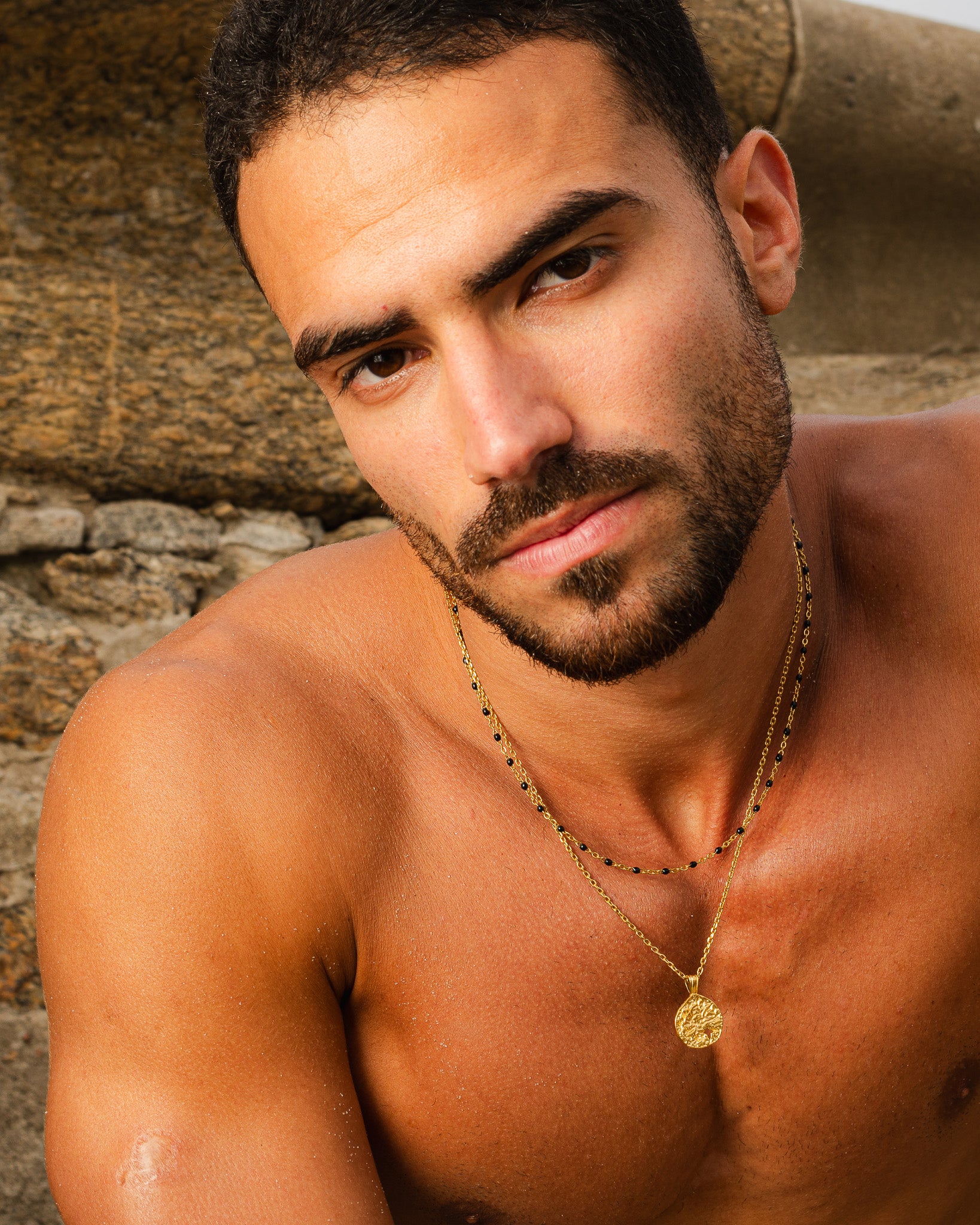 Gold pendant with a textured surface and star cutout on a layered gold chain around the neck