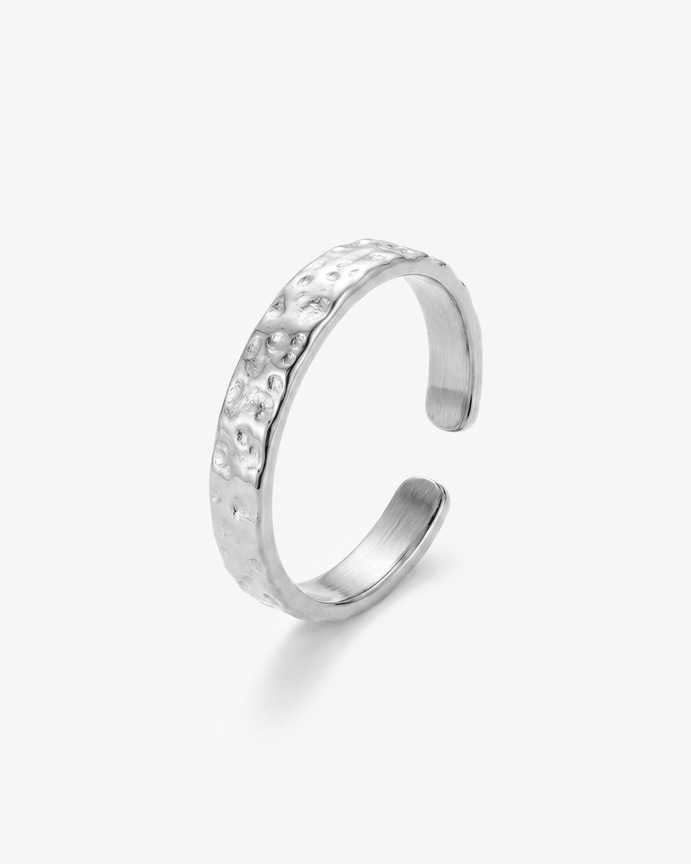 Anillo plateado martillado con superficie orgánica texturizada sobre fondo blanco.