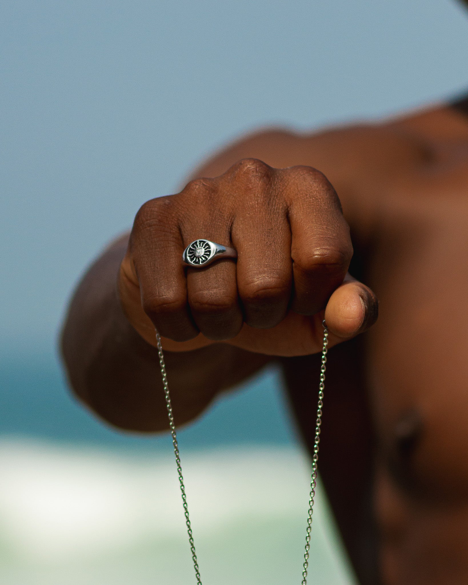 Close-up of Helio Silver Ring on the finger with a blue background.