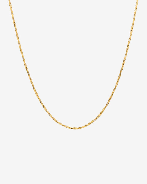 Minimal gold chain with a clean flat-link profile against a light background