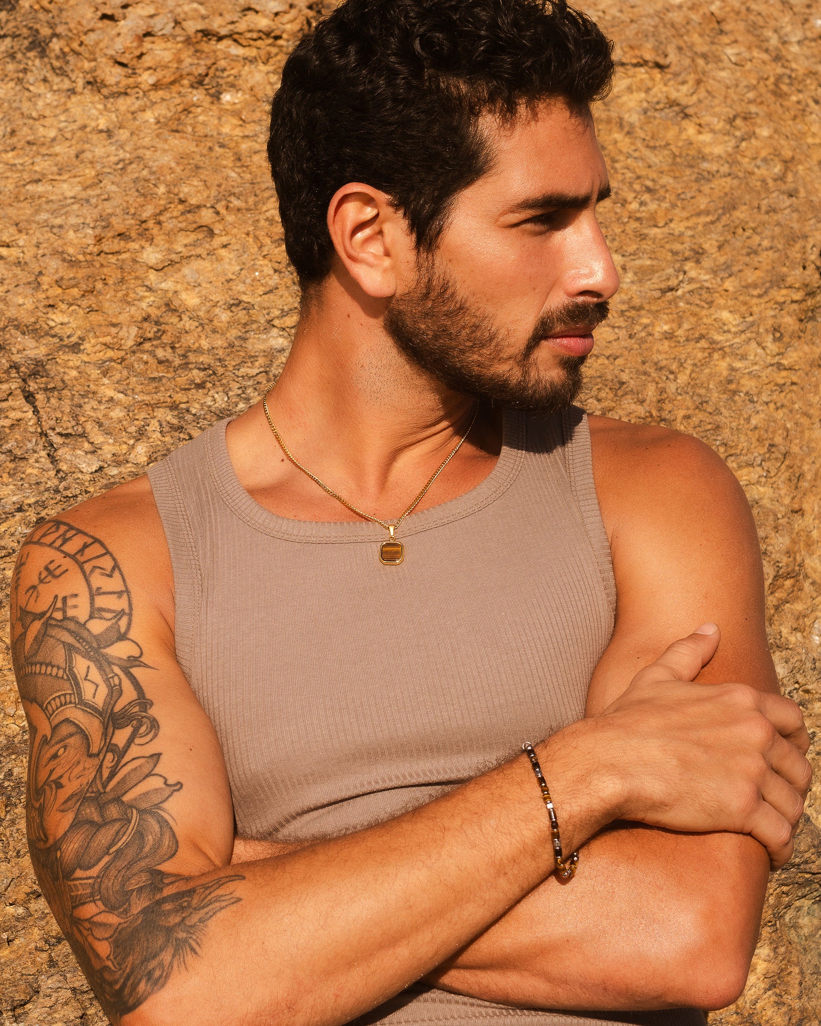 Profile view of a man wearing the NOVA GOLD NECKLACE against a rocky backdrop.