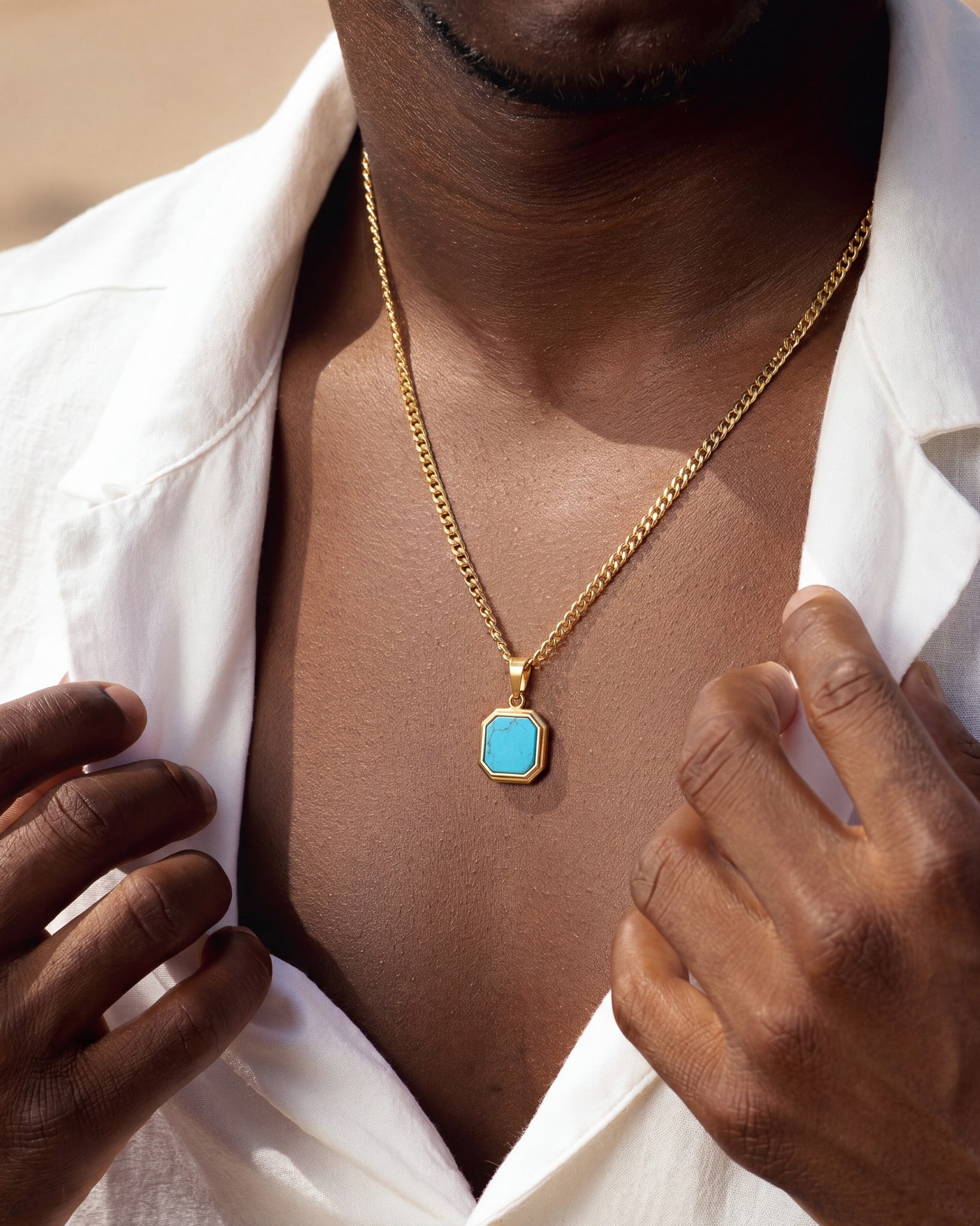 Model wearing Nova Gold Necklace with turquoise pendant resting on the chest under a white shirt.