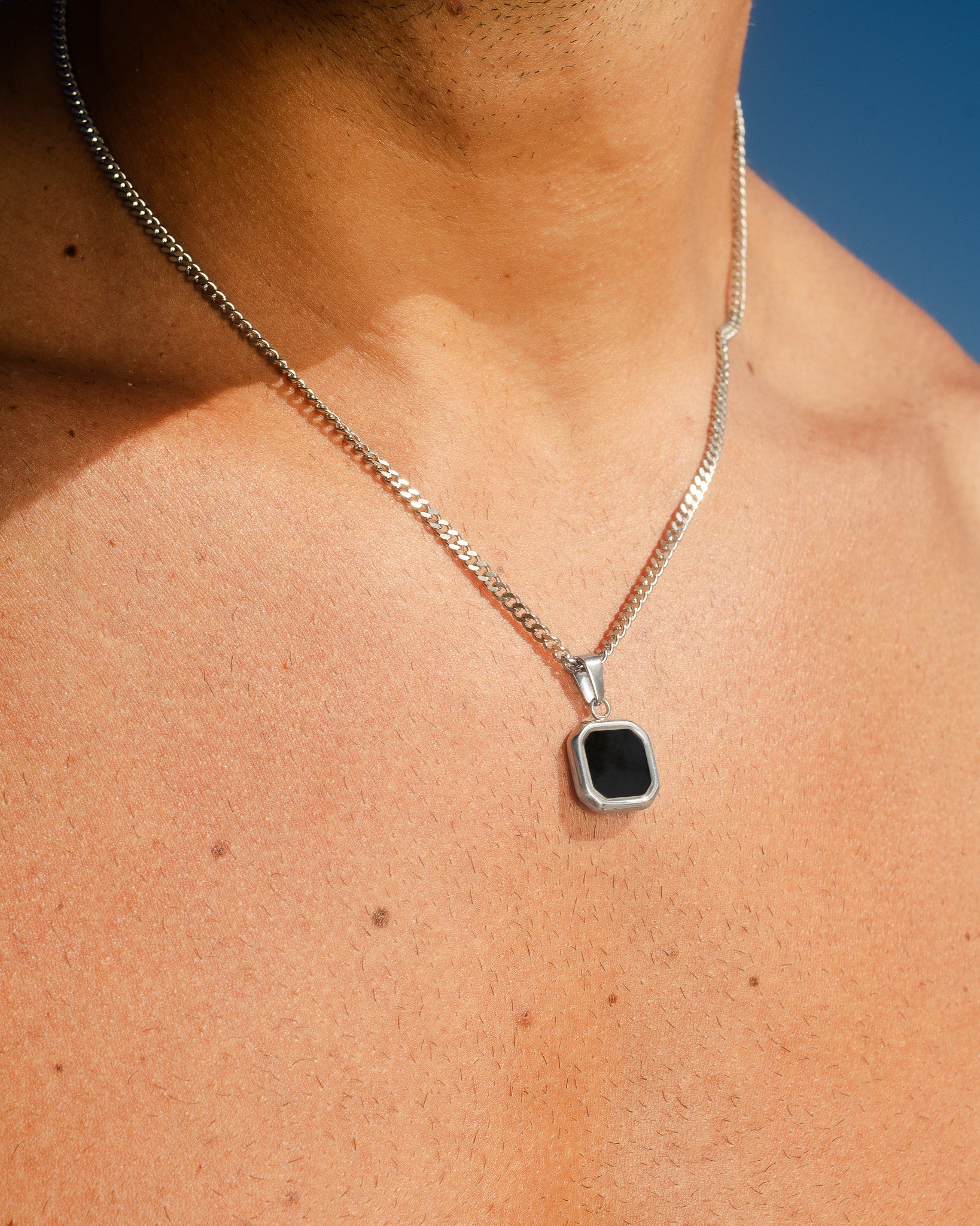 Nova Silver Necklace resting on the neck with the chain visible against a clear blue sky