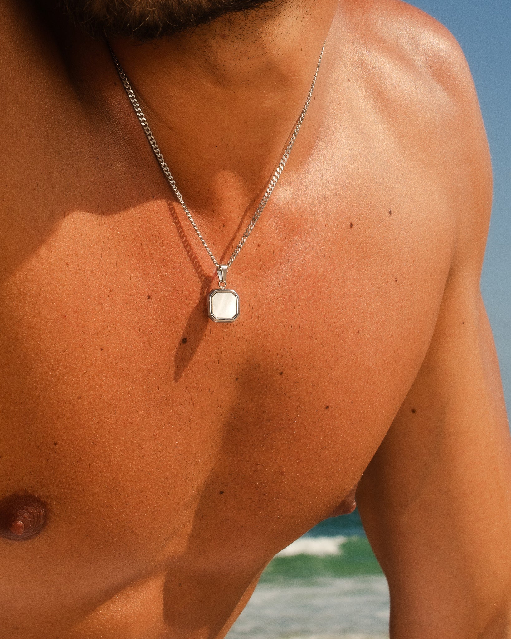 Silver Nova necklace with a square framed pendant worn on a man’s chest.